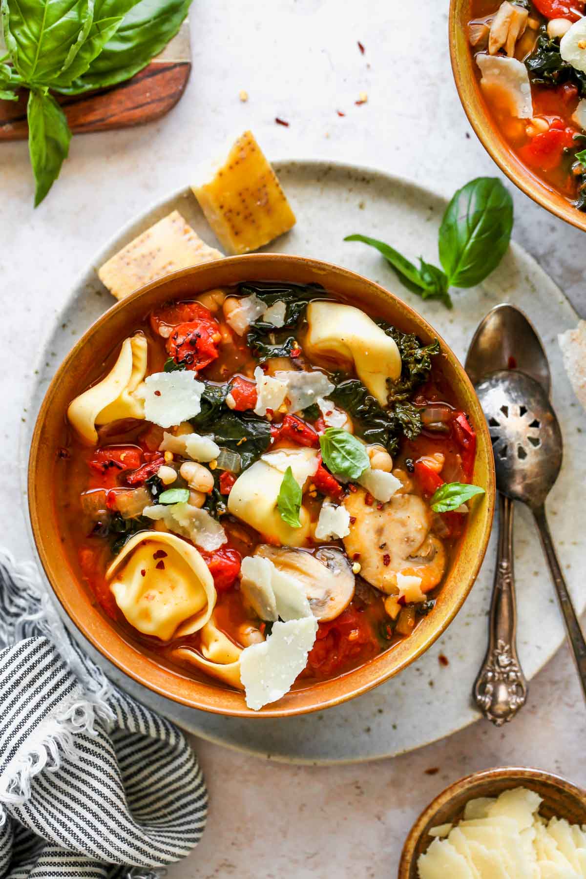 Tuscan tomato soup with tortellini, white beans, and kale in a gold bowl