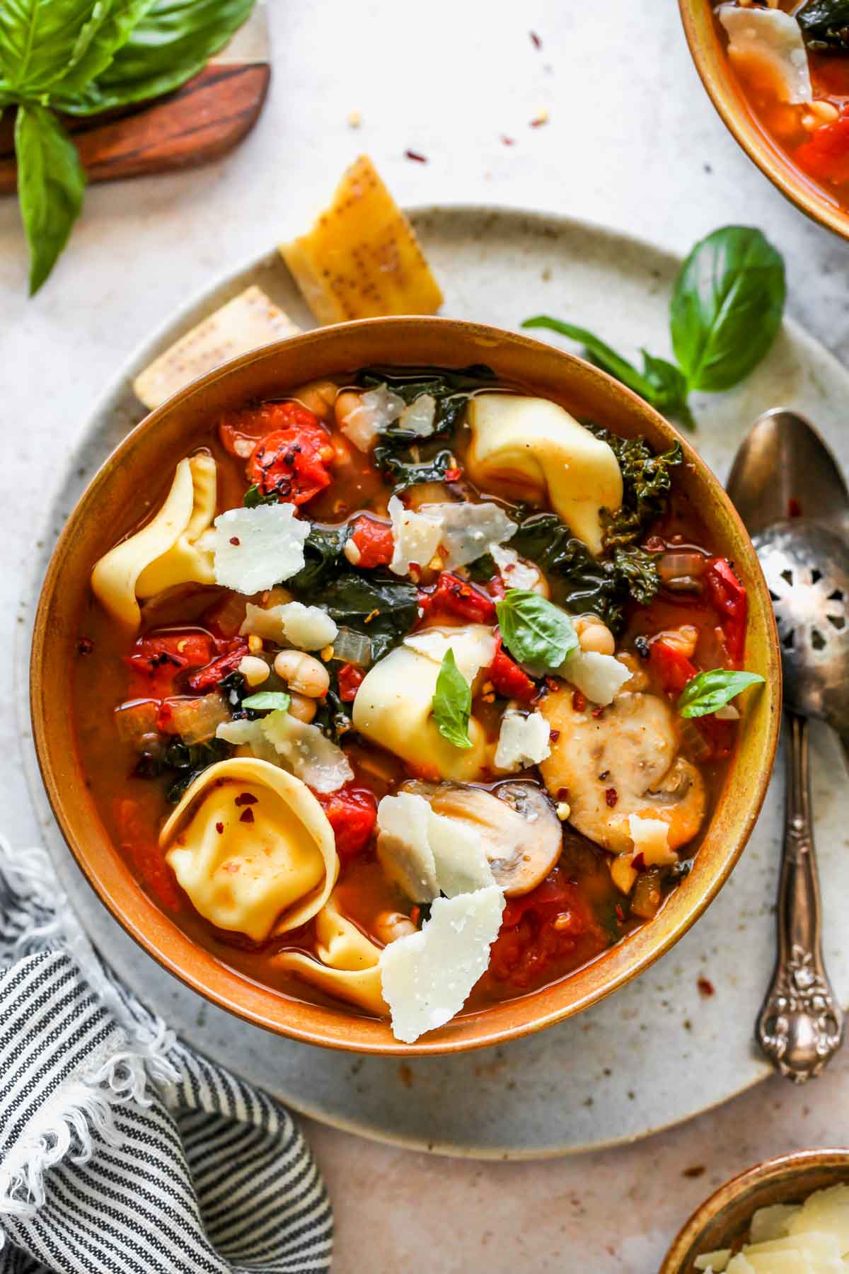 Tortellini and tomato soup in a gold bowl topped with basil