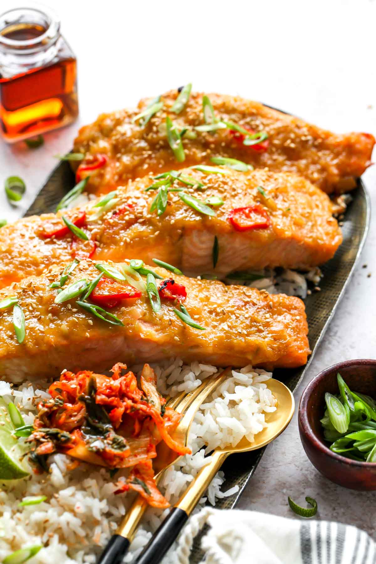 Three salmon fillets on a platter topped with green onion