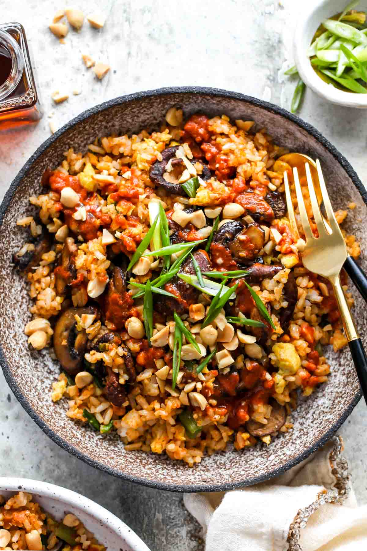 Mushroom fried rice on a plate topped with red curry peanut sauce