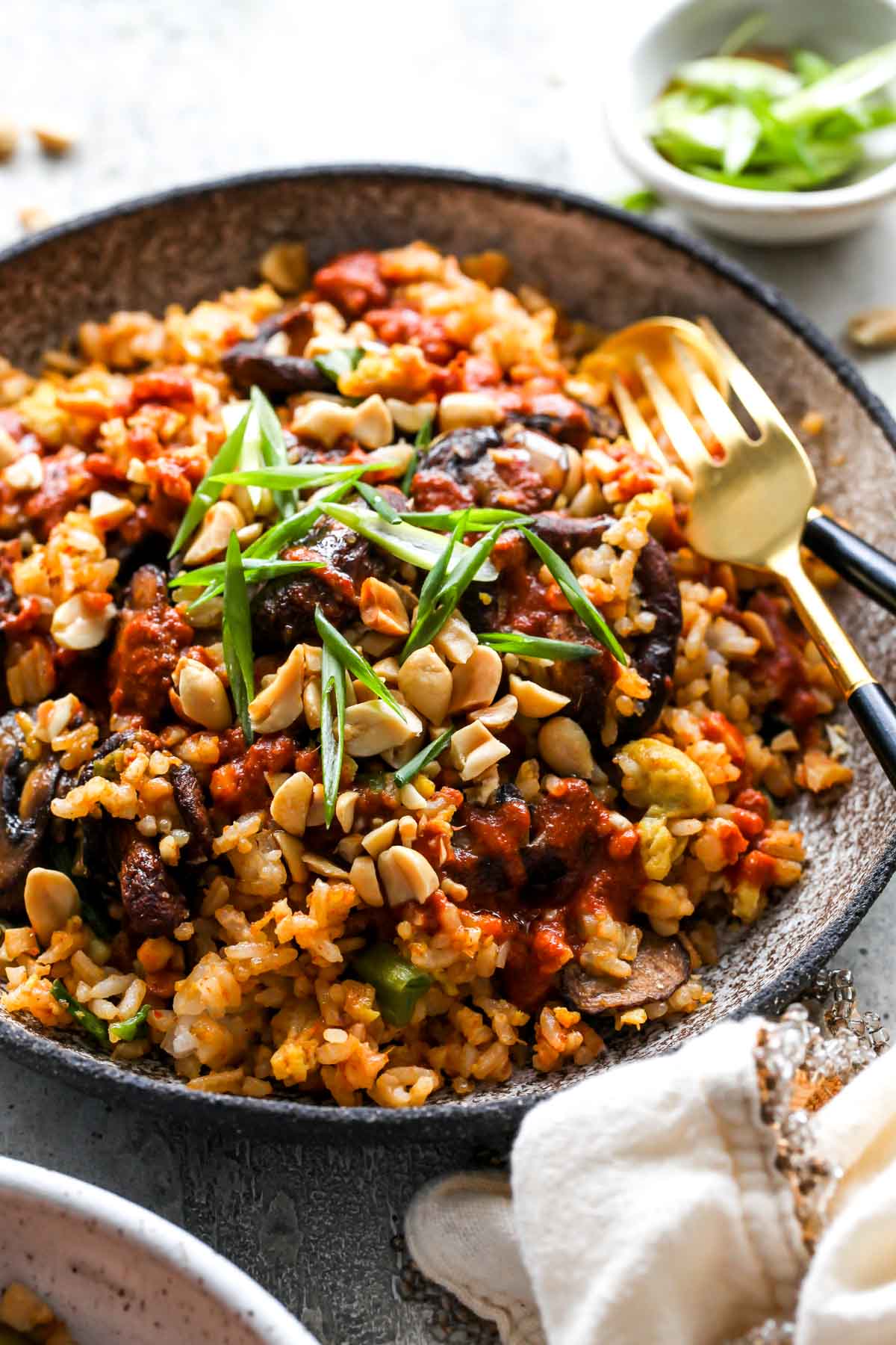 Fork digging into a plate of vegetable fried rice in a silver bowl