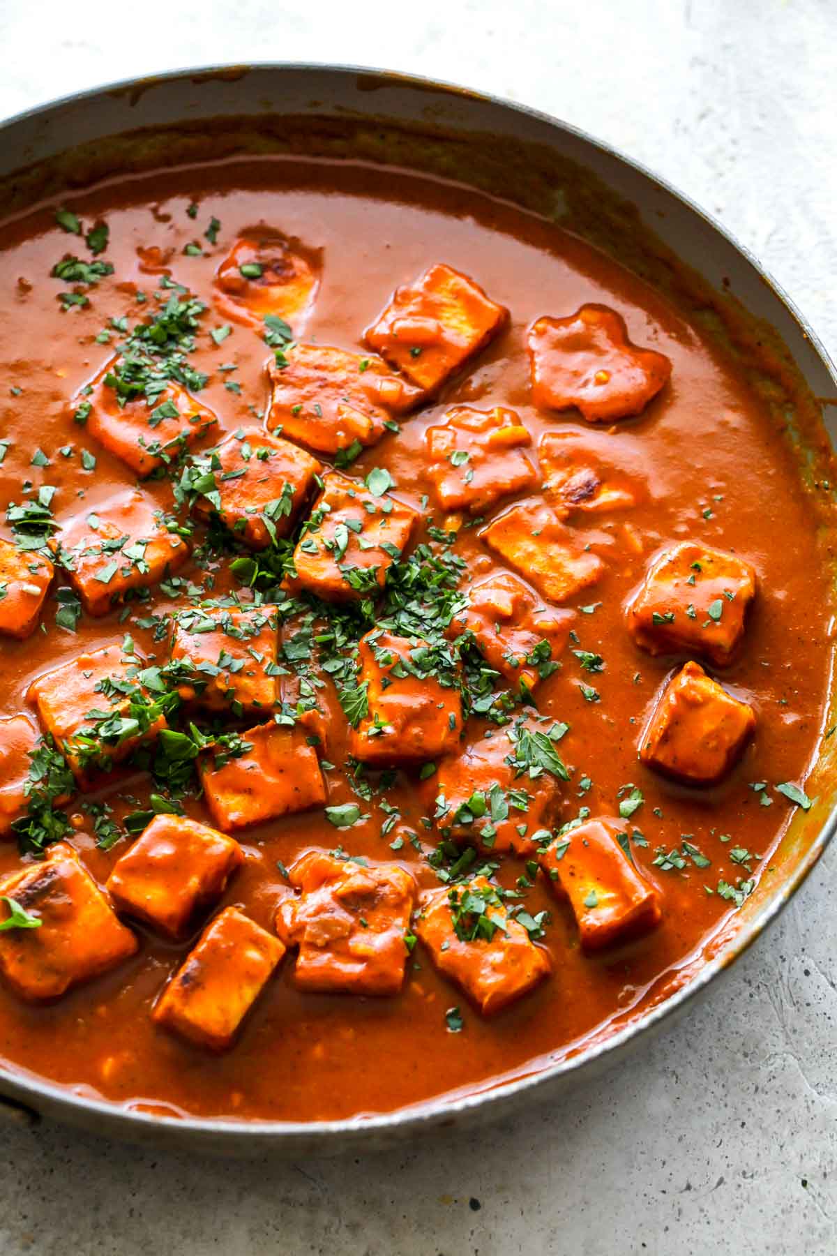 Tofu cubes in masala sauce topped with cilantro in a skillet