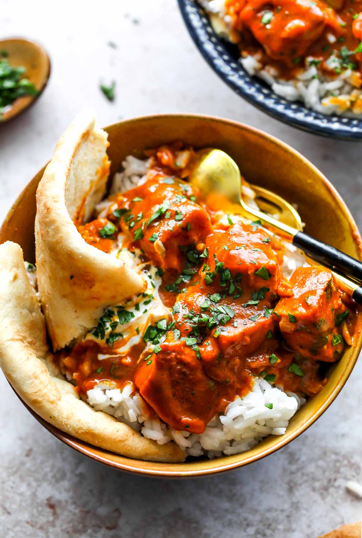 Tofu tikka masala over rice in a gold bowl served with naan