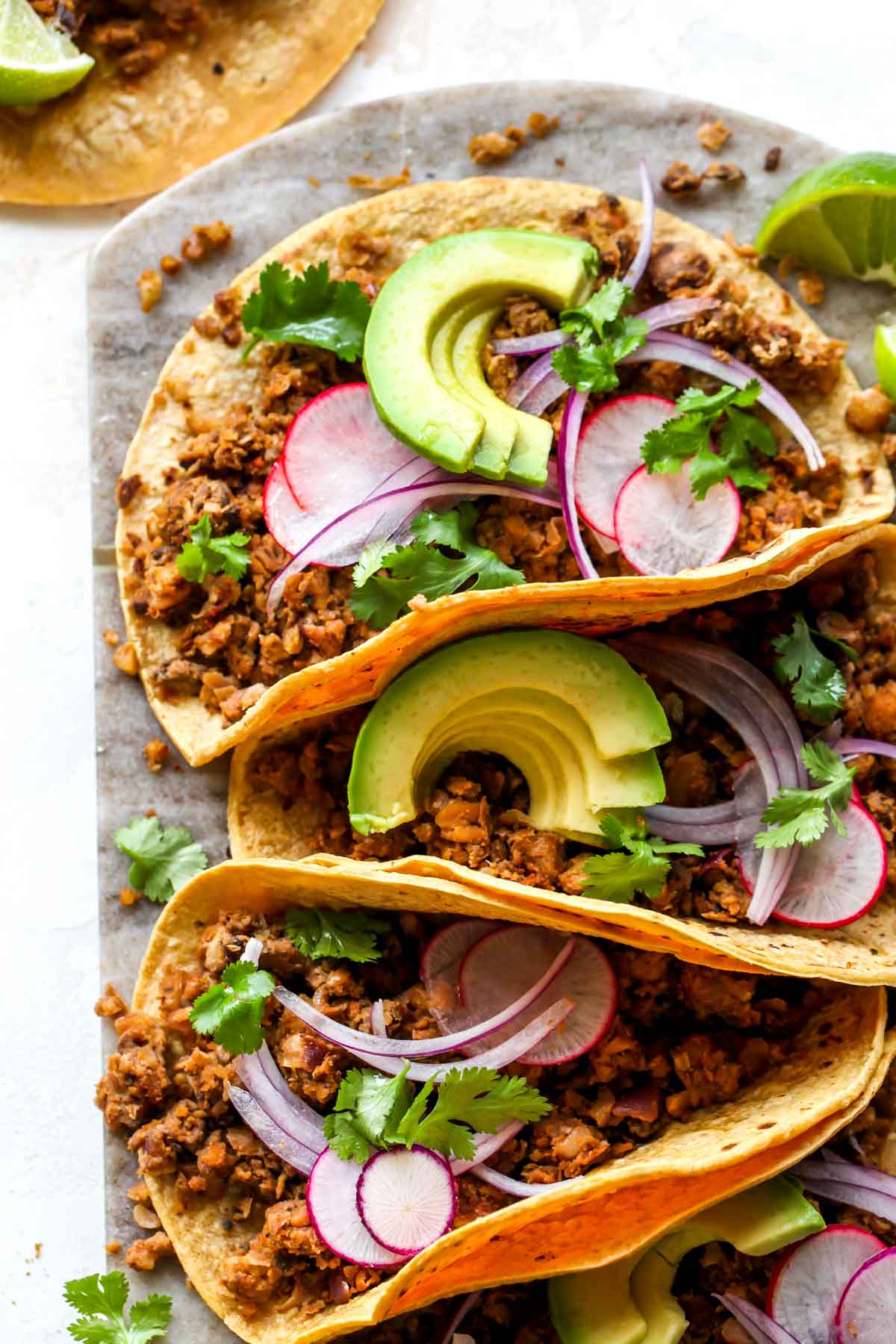 Three vegetarian tacos filled with plant-based chorizo and topped with avocado and red onion