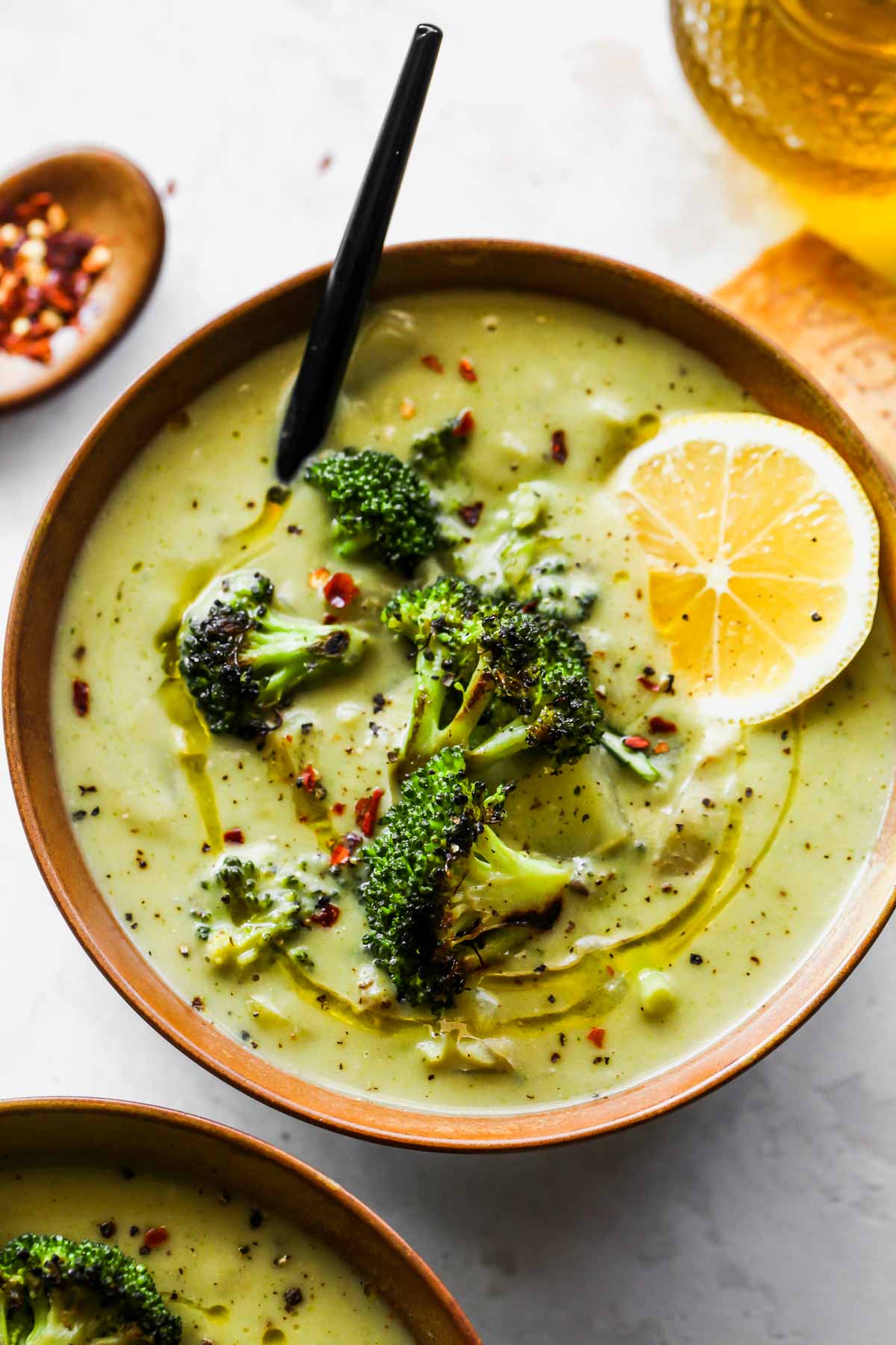 Healthy broccoli cheese soup in a gold bowl topped with lemon wedge