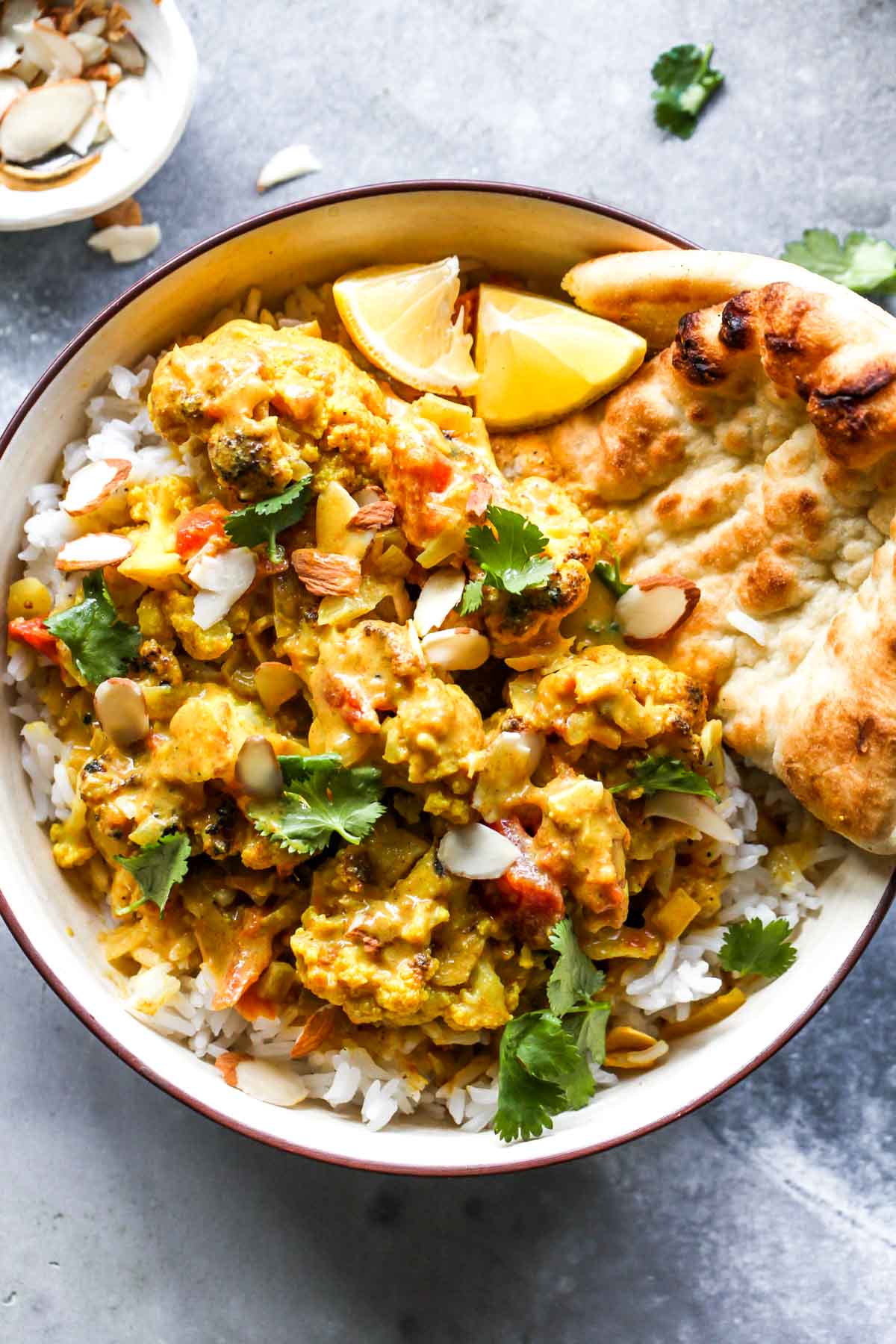 Cauliflower curry over rice served with naan and cilantro