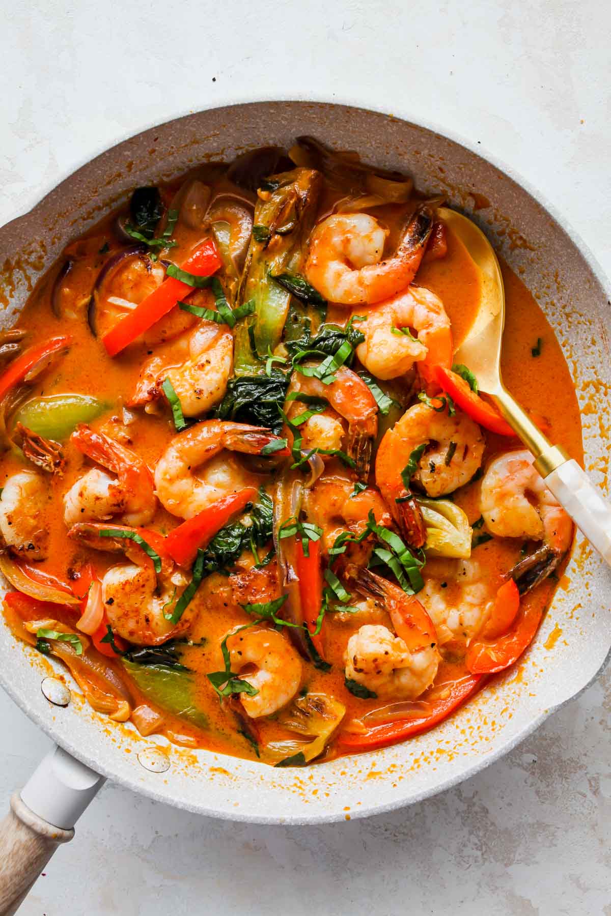 Completed shrimp curry being spooned out of a skillet