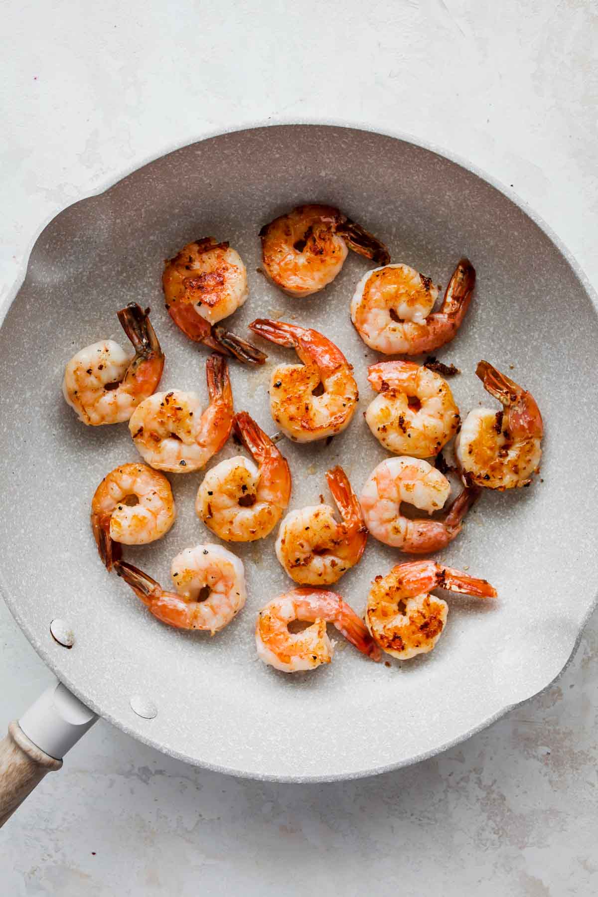 Prawns being pan-seared in a large white skillet