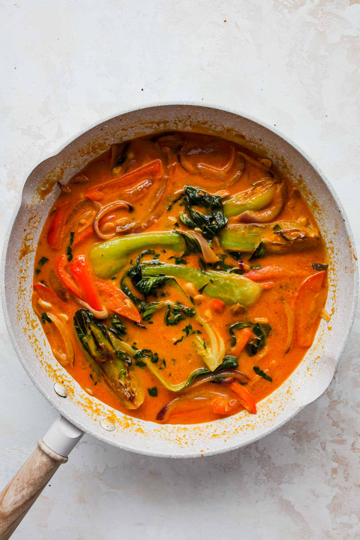 Coconut milk being added to a skillet of veggies
