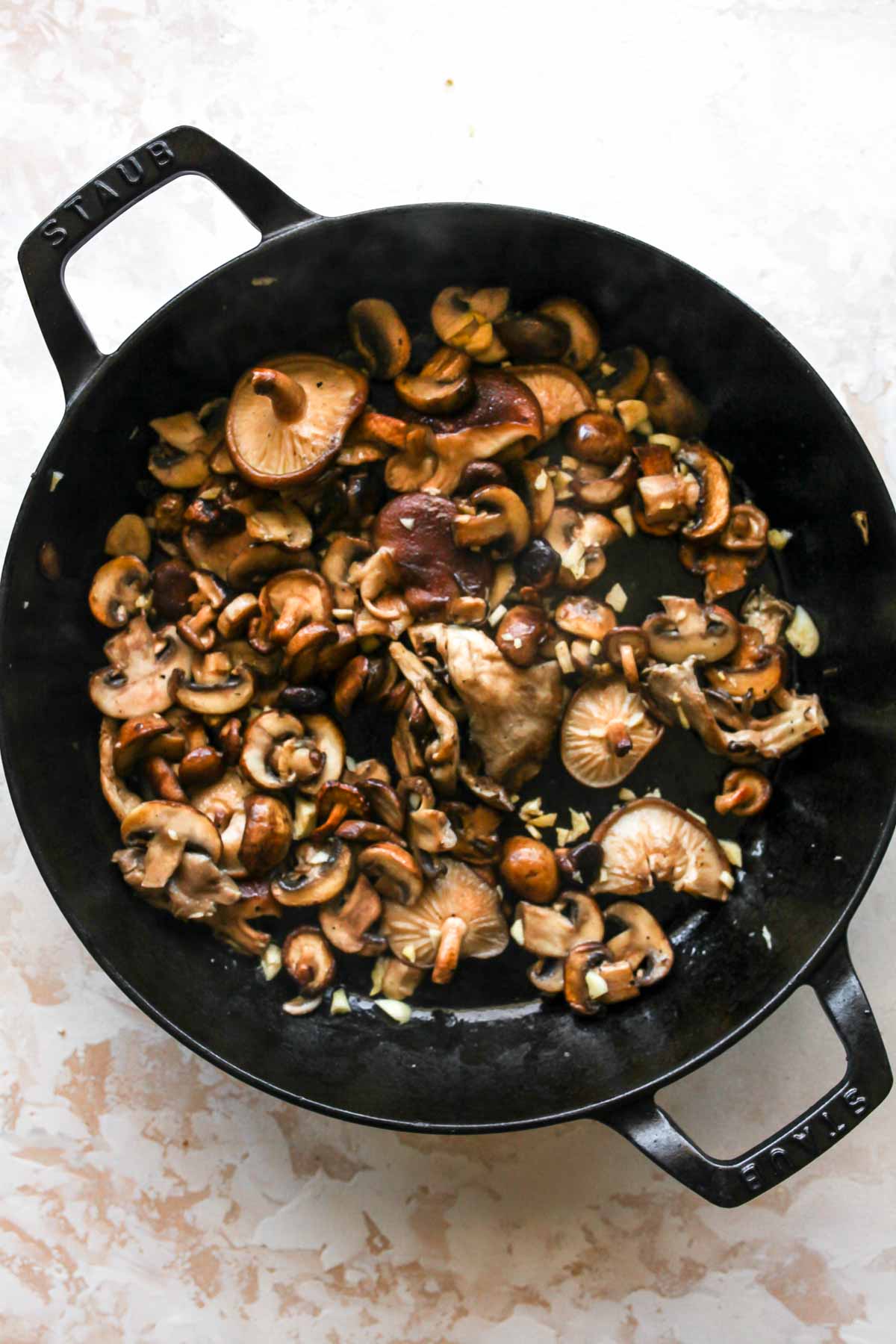 Mushrooms being sauteed in a cast-iron skillet