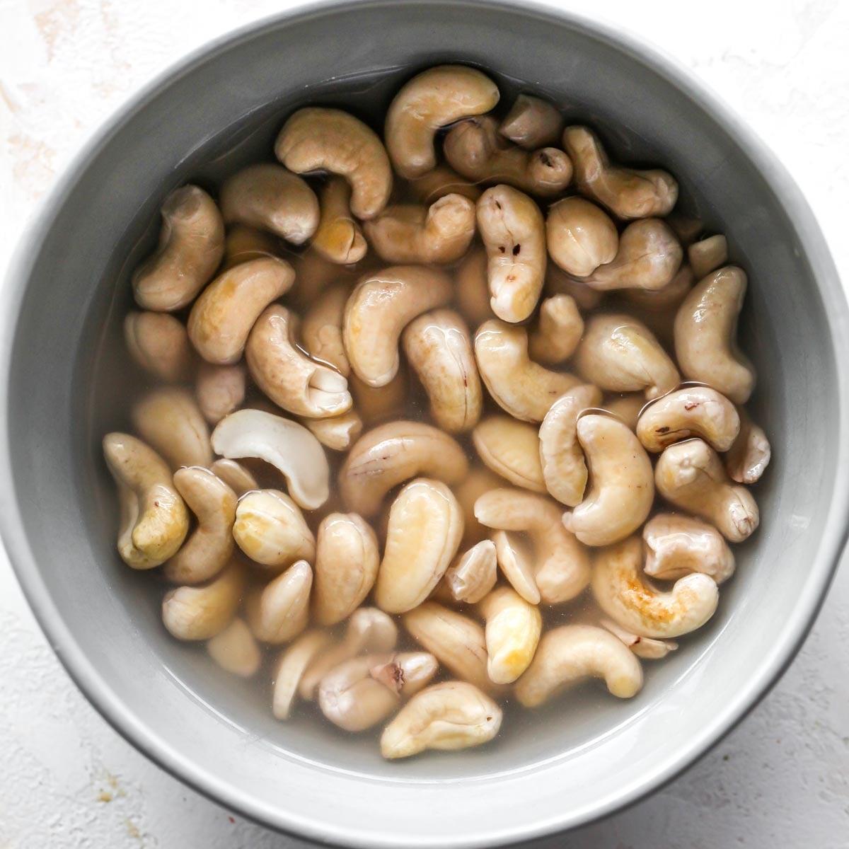Cashews soaking in water in a grey bowl