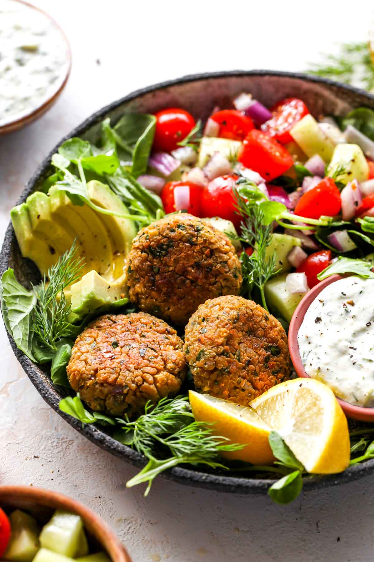 Falafel over a bed of greens with sliced avocado