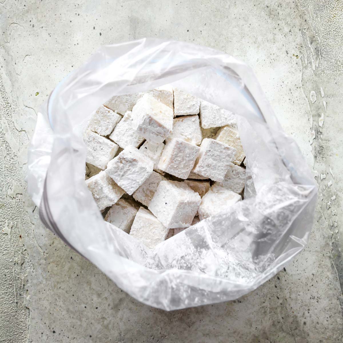 Cubes of tofu tossed in corn starch in a gallon-sized bag