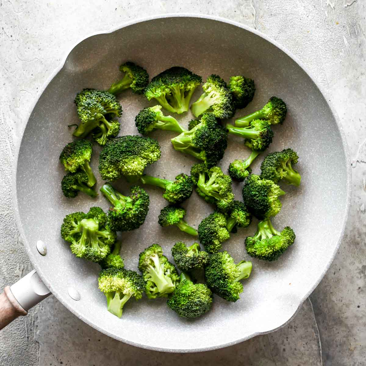 Broccoli florets being sautéed in a skillet