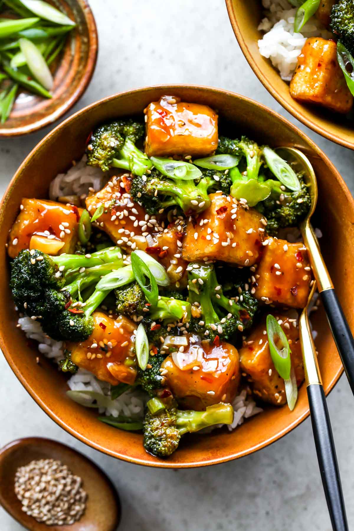 Asian tofu and broccoli in a gold bowl topped with sesame seeds