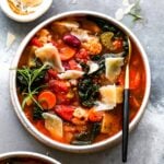 Bowl of vegetable soup with Parmesan and herb garnish