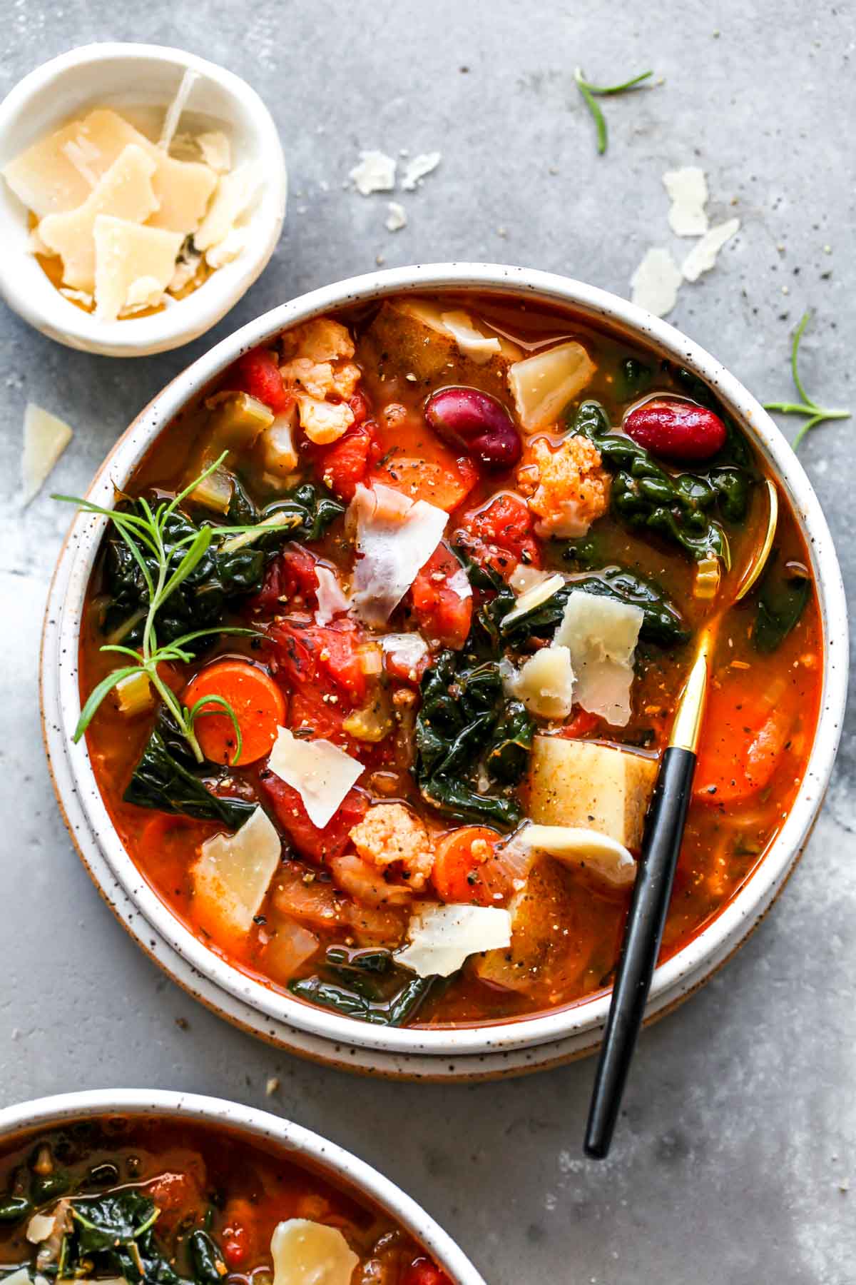 Bowl of vegetarian soup with potatoes, kale, and tomatoes
