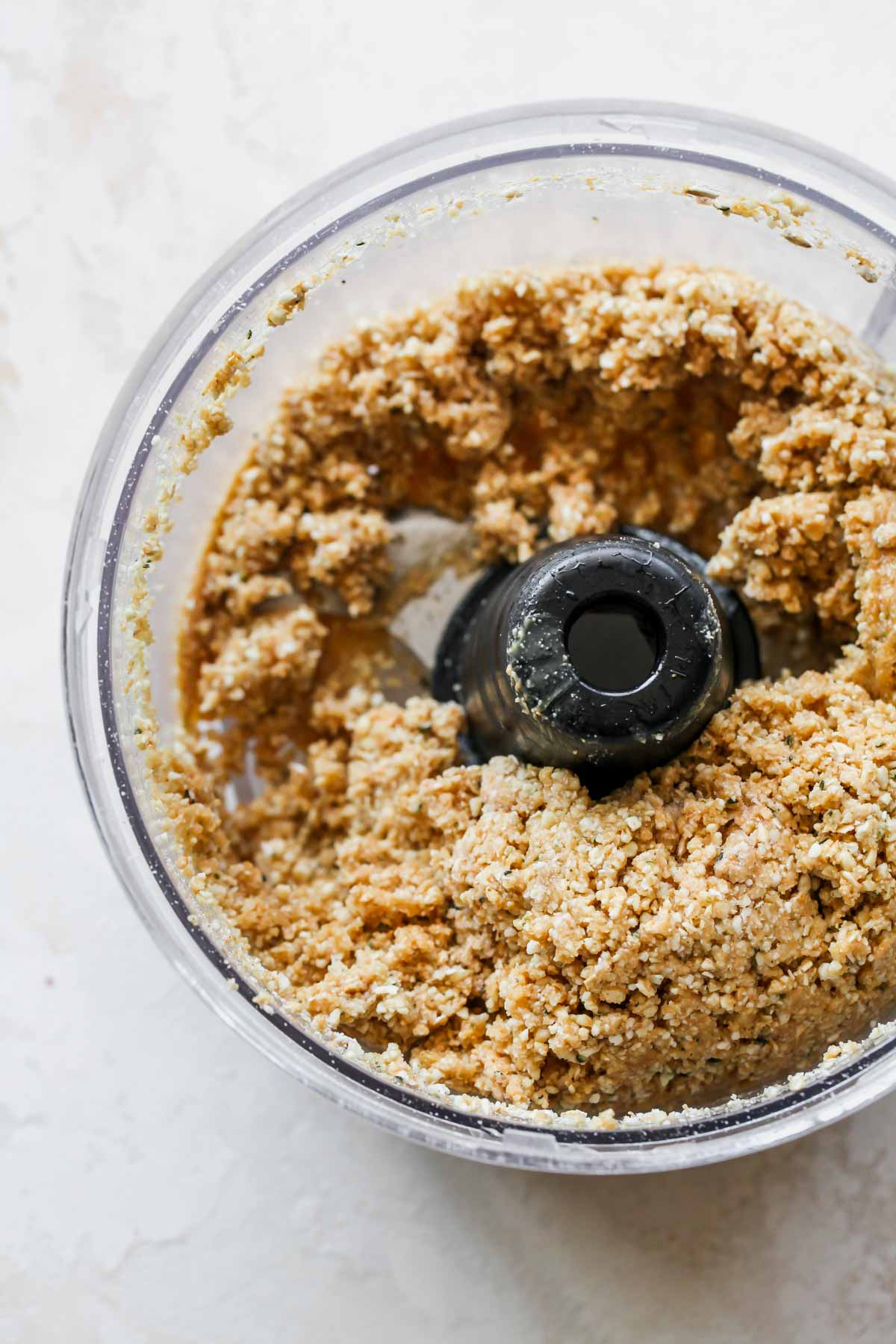 Cashew butter and maple syrup blended with dry ingredients in a food processor