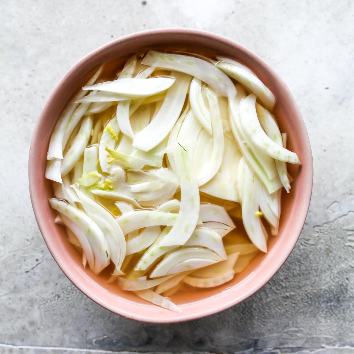 Shaved fennel being quick-pickled in a bowl