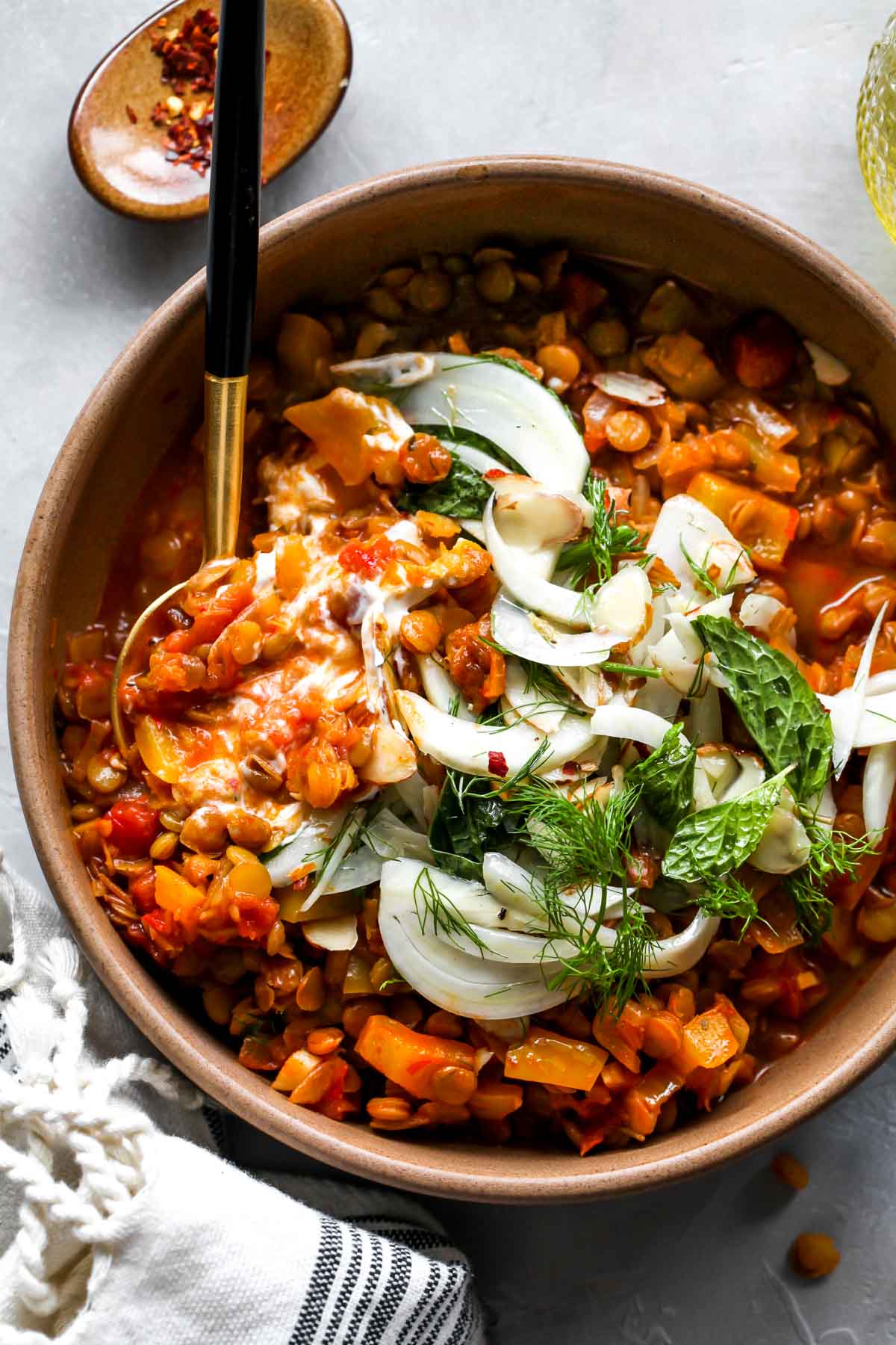 Yogurt mixed into stewed lentils in a gold bowl