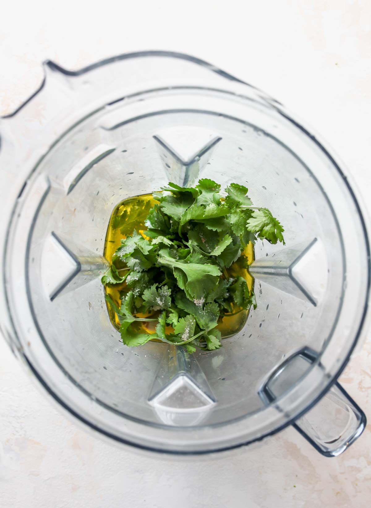 Cilantro, oil, and spices being combined in a blender