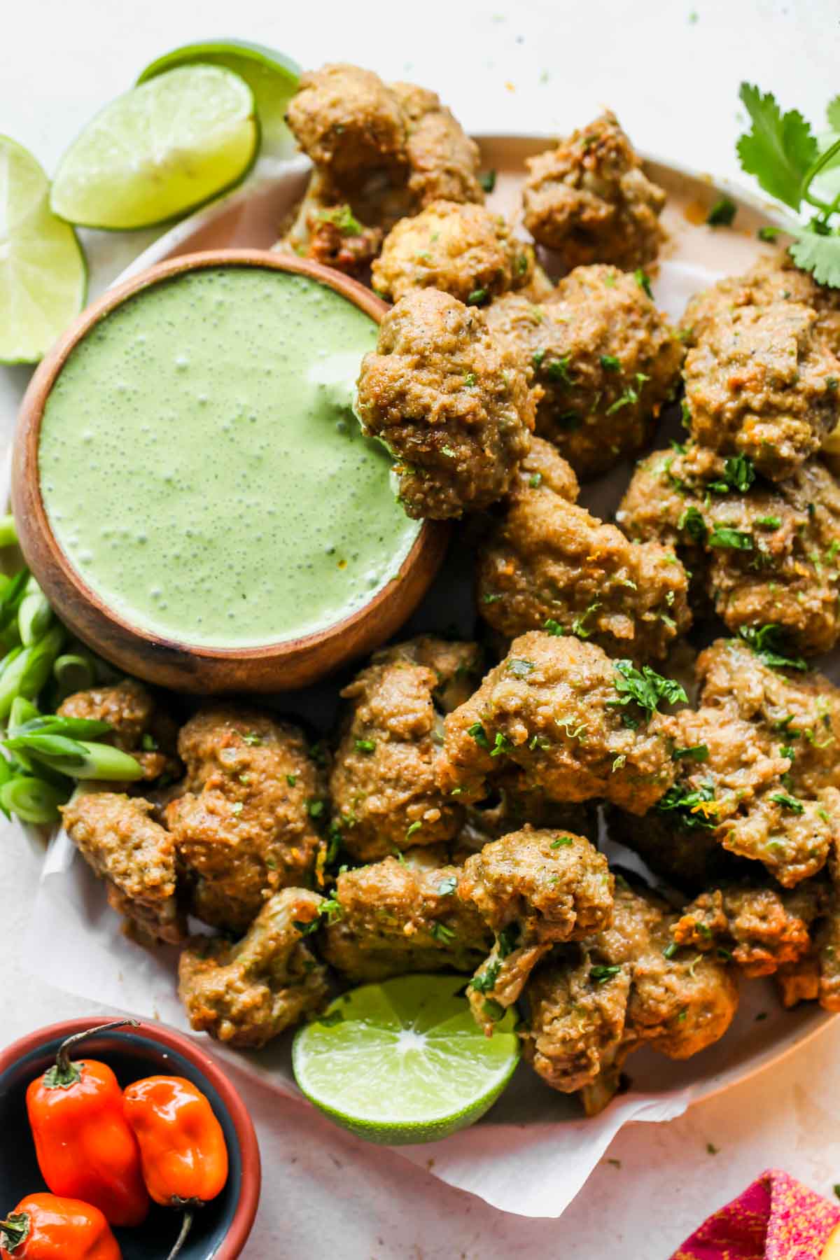 Cauliflower wings on a platter with a bowl of mojo sauce for dipping