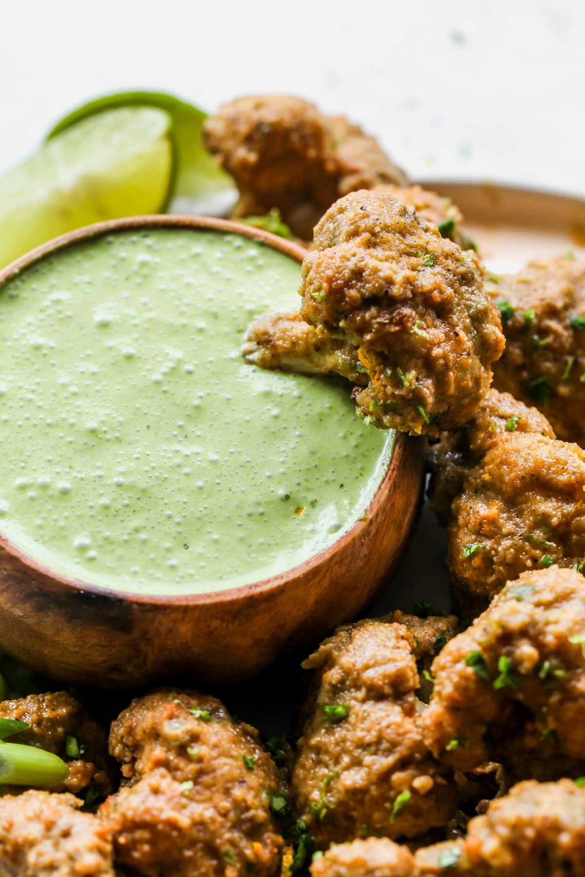 One jerk cauliflower wing being dipped into a bowl of Mojo Sauce
