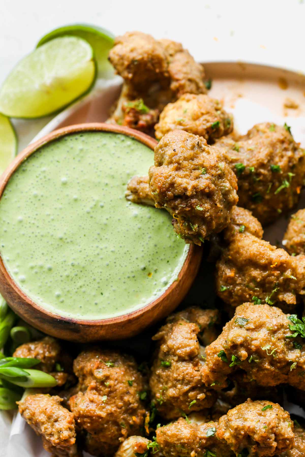 Jerk cauliflower wing being dipped in mojo sauce