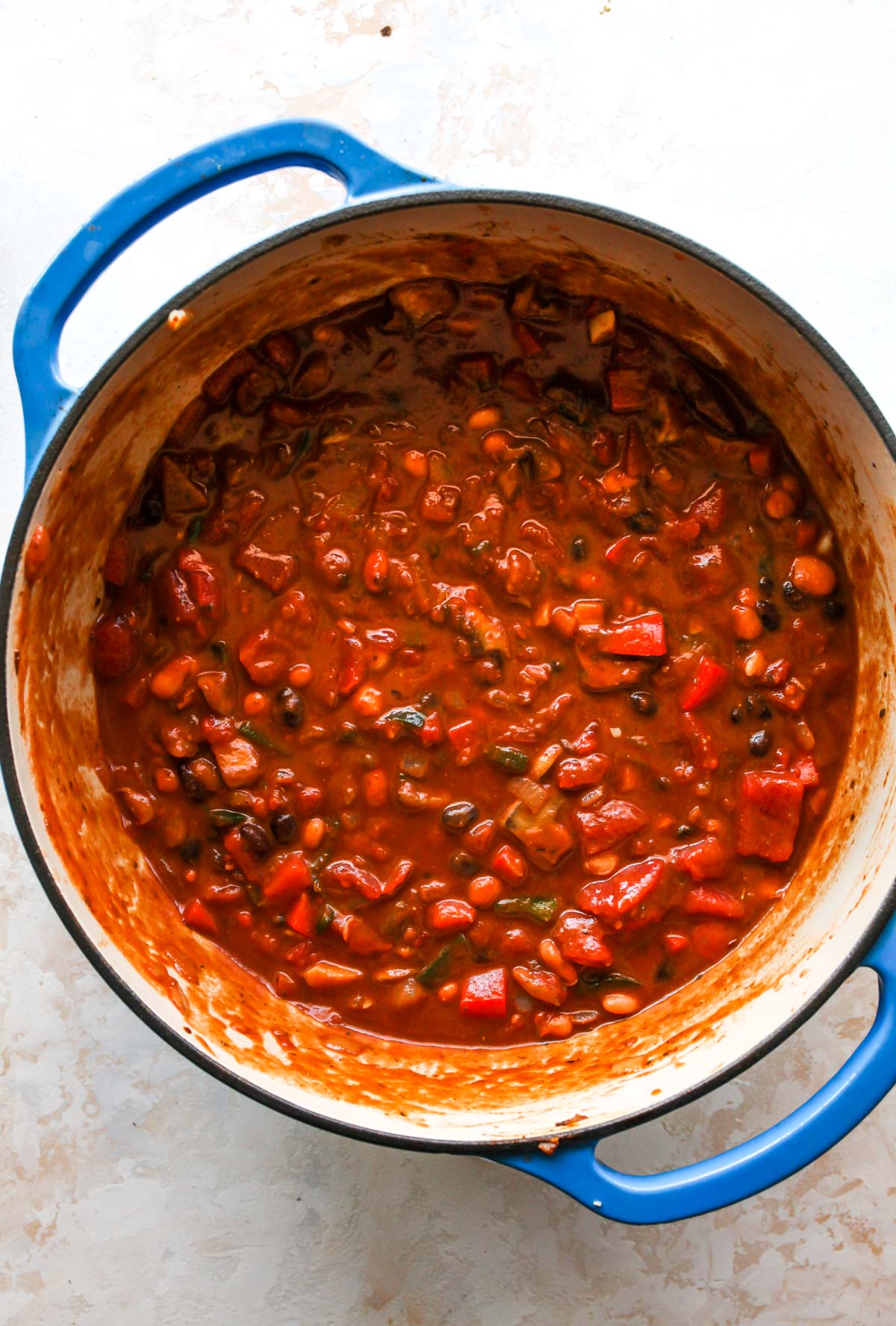 Tomato sauce, diced tomatoes, and beans being added to pot