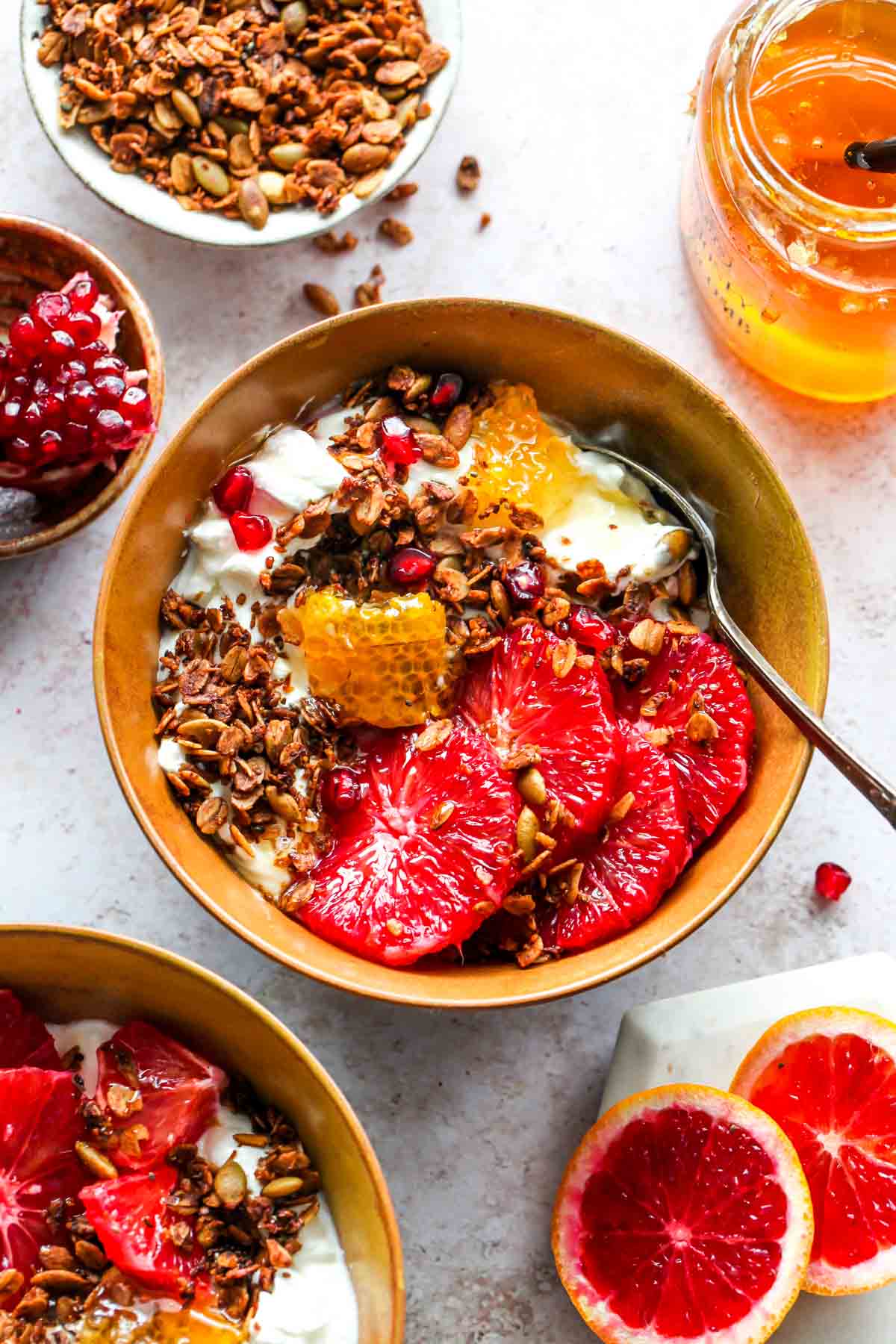 Yogurt bowl topped with citrus wedges, granola, and honey