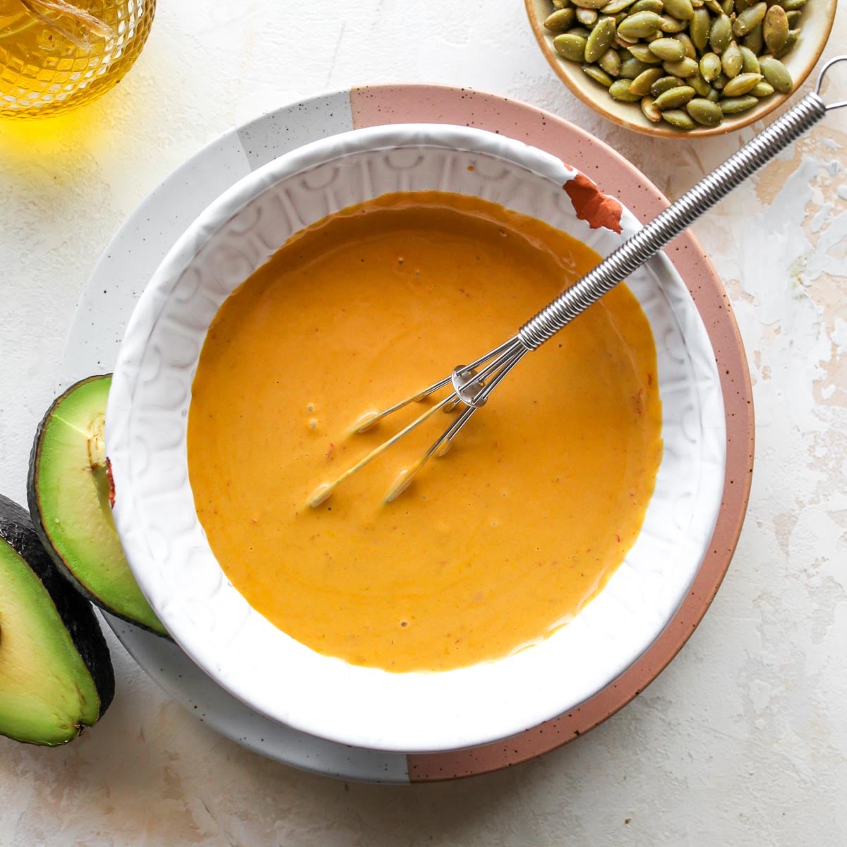 Golden tahini sauce being whisked in a white bowl