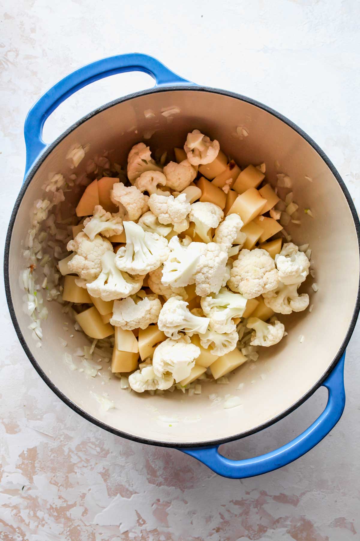 Cauliflower florets and potatoes being mixed in a pot