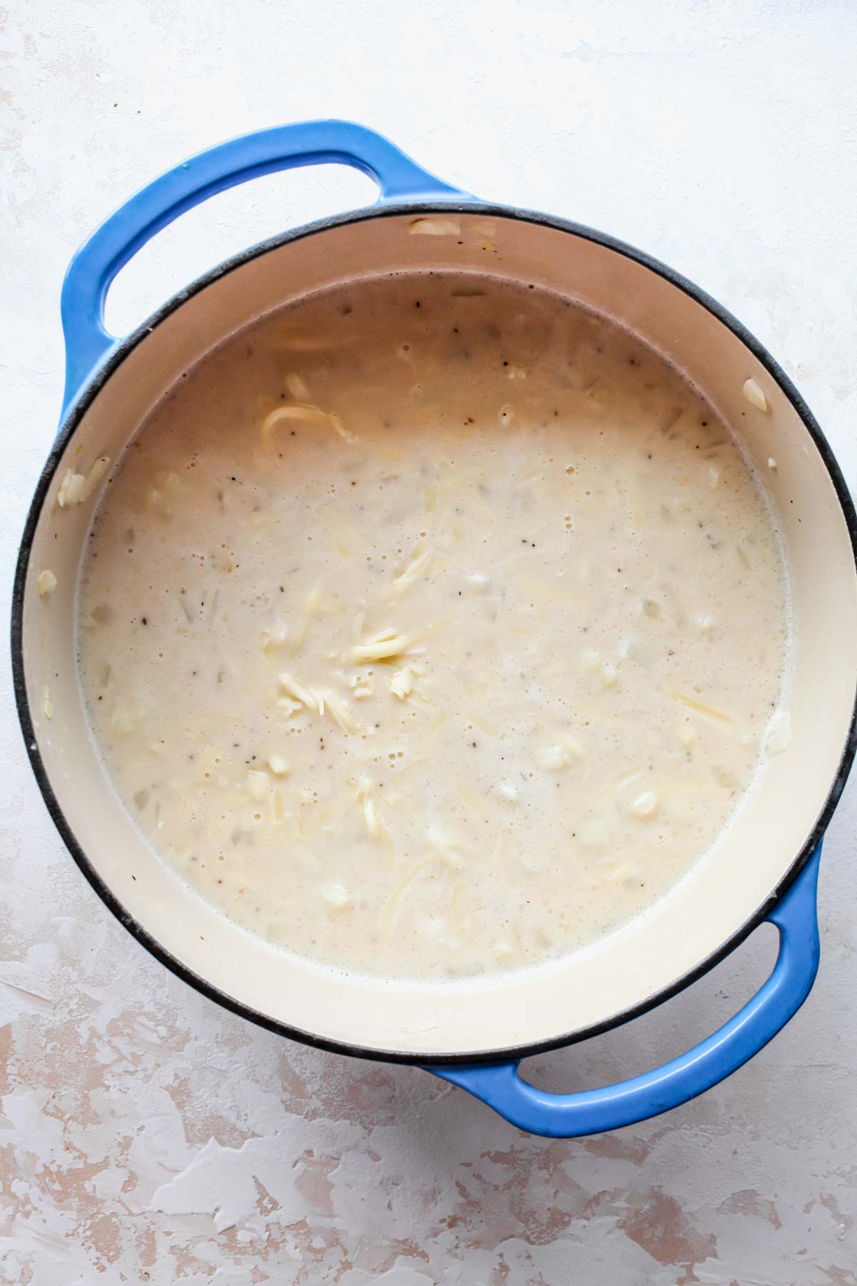 Milk and cheddar cheese being mixed in a pot of soup