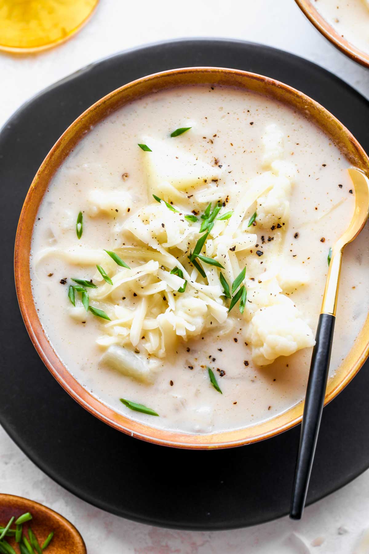 Bowl of cream of cauliflower soup topped with chives and black pepper