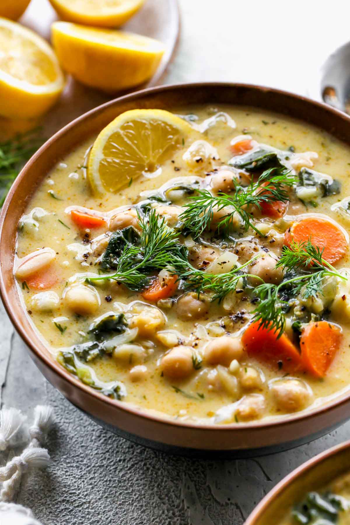 Bowls of chickpea soup with lemon wedge garnishes on the side