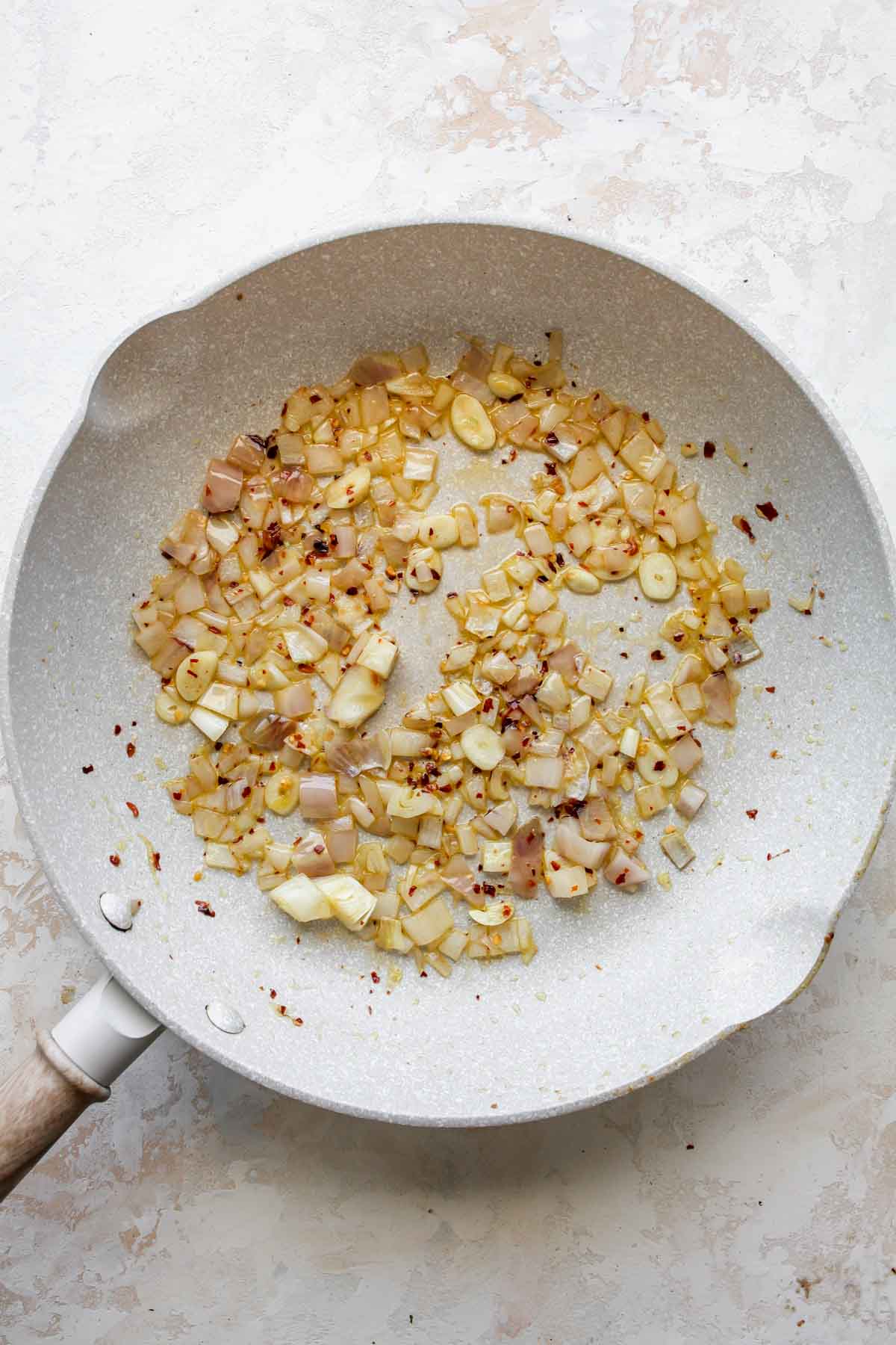 Shallots, garlic, and red pepper flakes being sautéed in a skillet