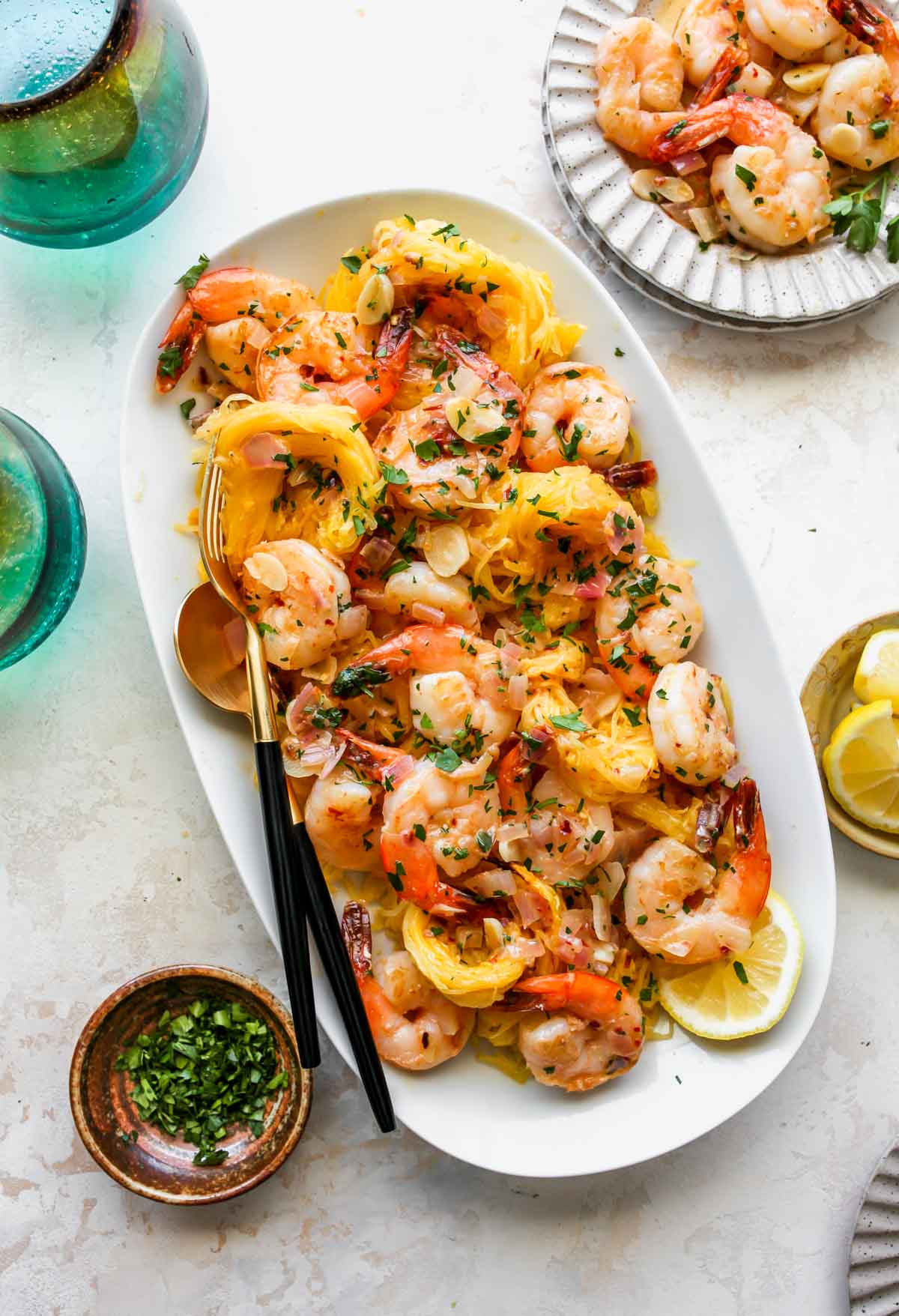 Platter of spaghetti squash topped with shrimp scampi, lemons, and parsley