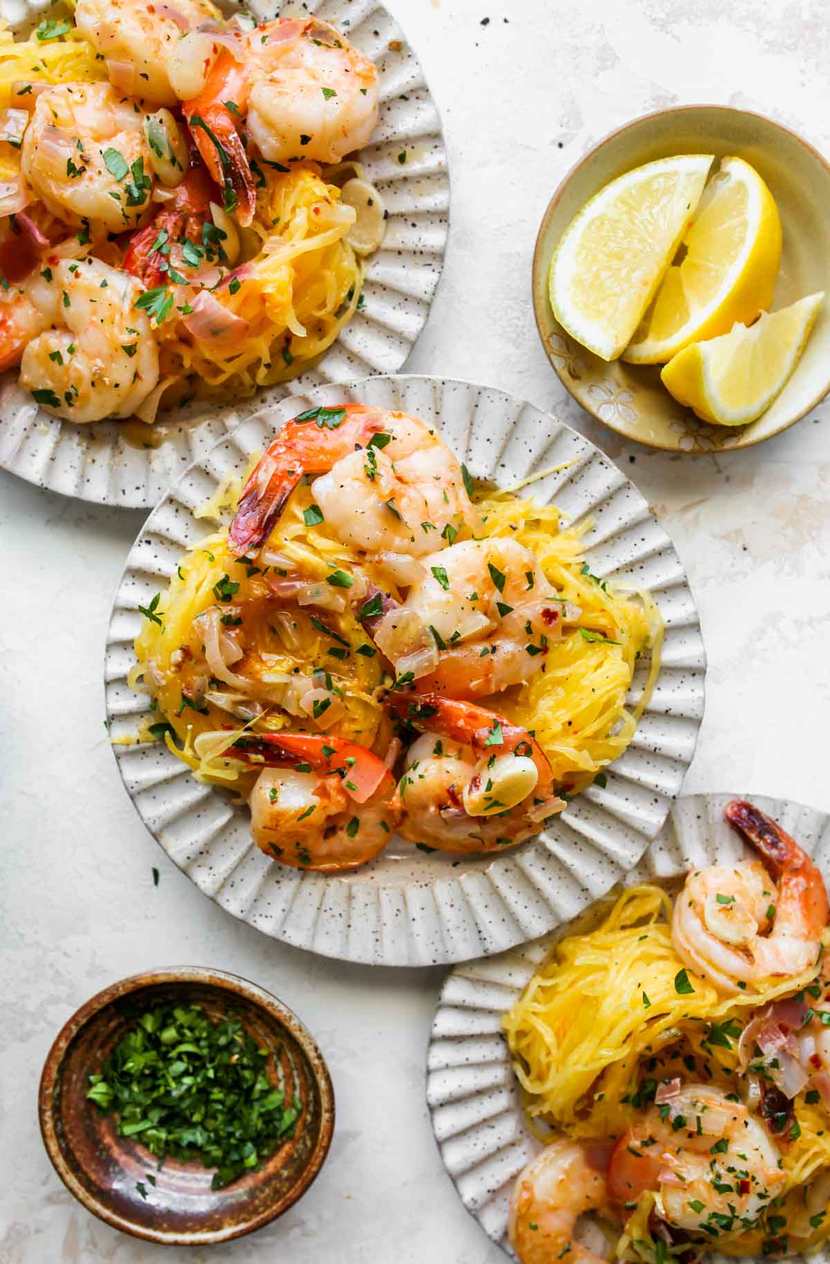 Three plates lined up with individual servings of spaghetti squash and shrimp