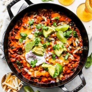 Spinach Artichoke Skillet Enchiladas topped with avocado, cilantro, and sour cream