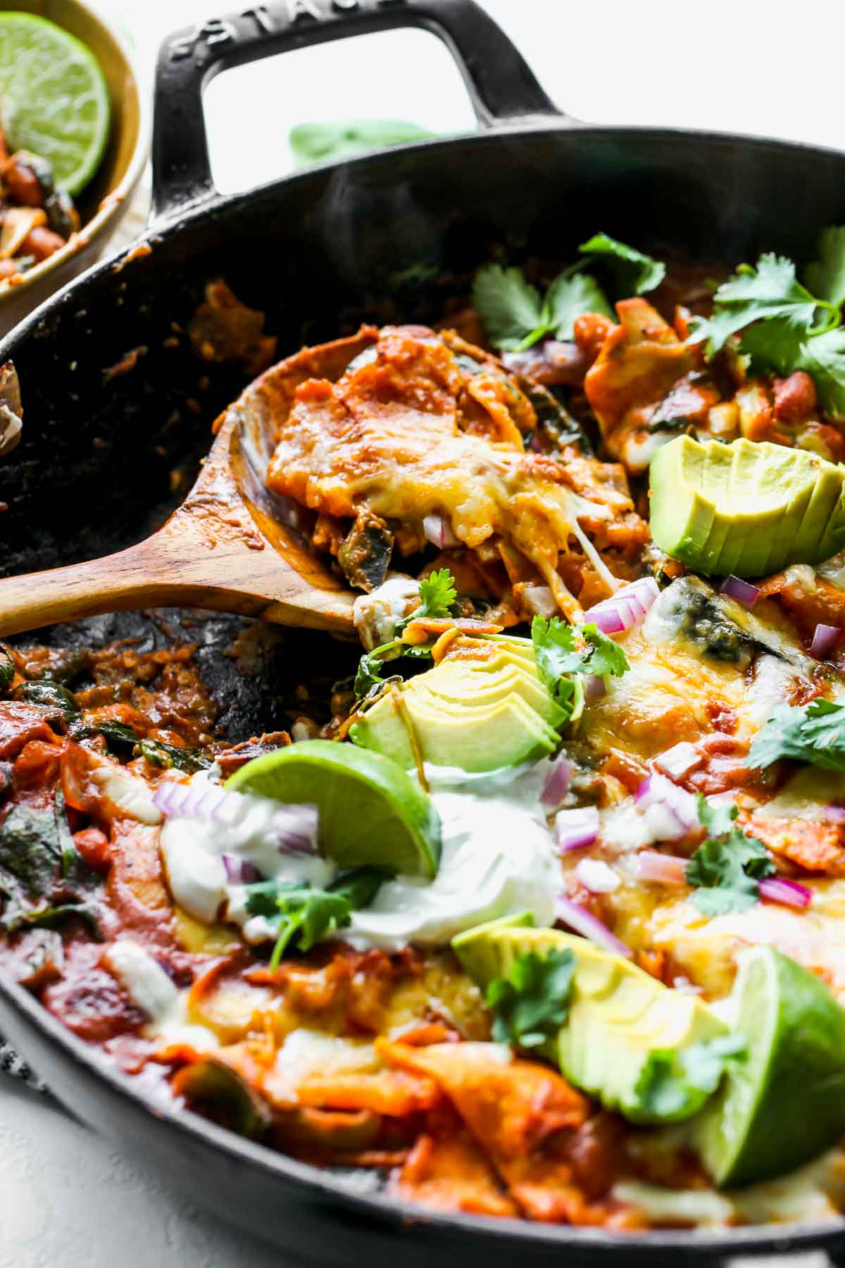Spoon taking a serving out of skillet enchiladas showing inside filling