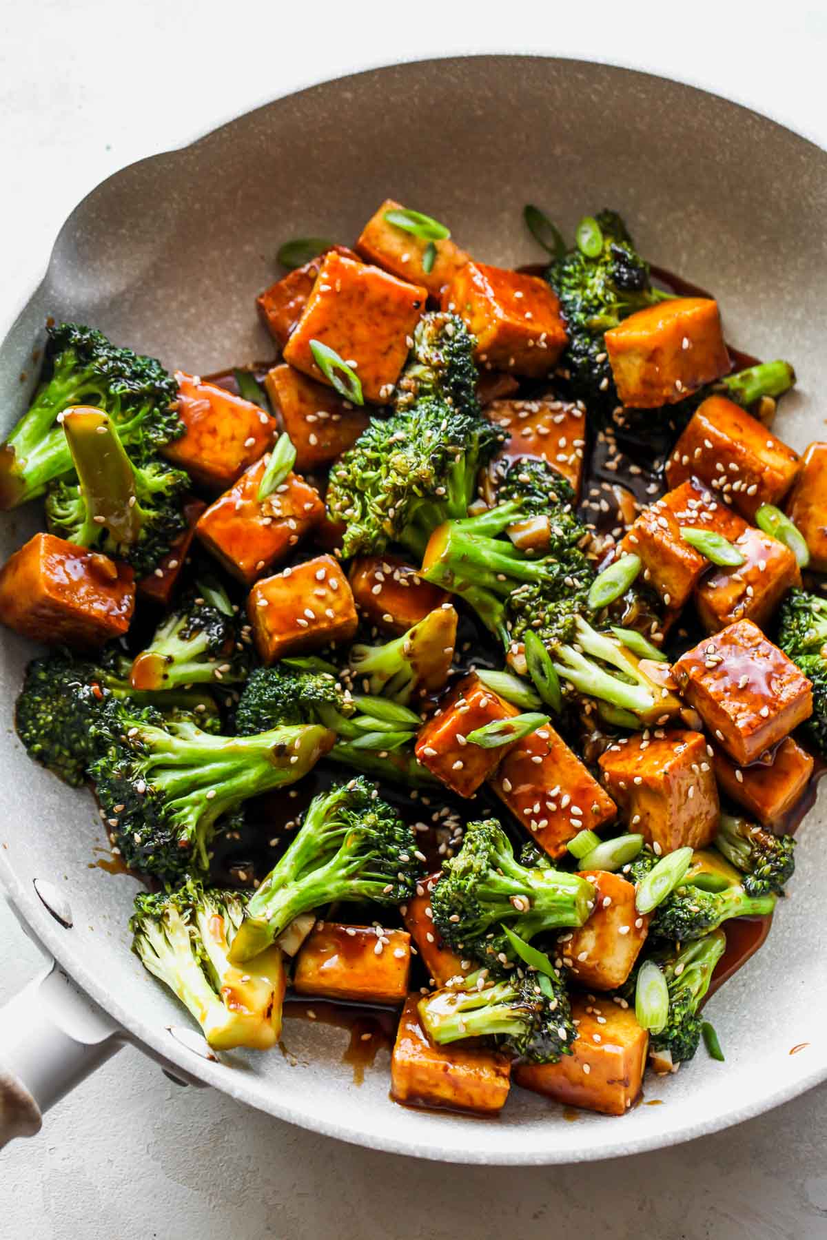 Teriyaki tofu and broccoli simmering in a white skillet