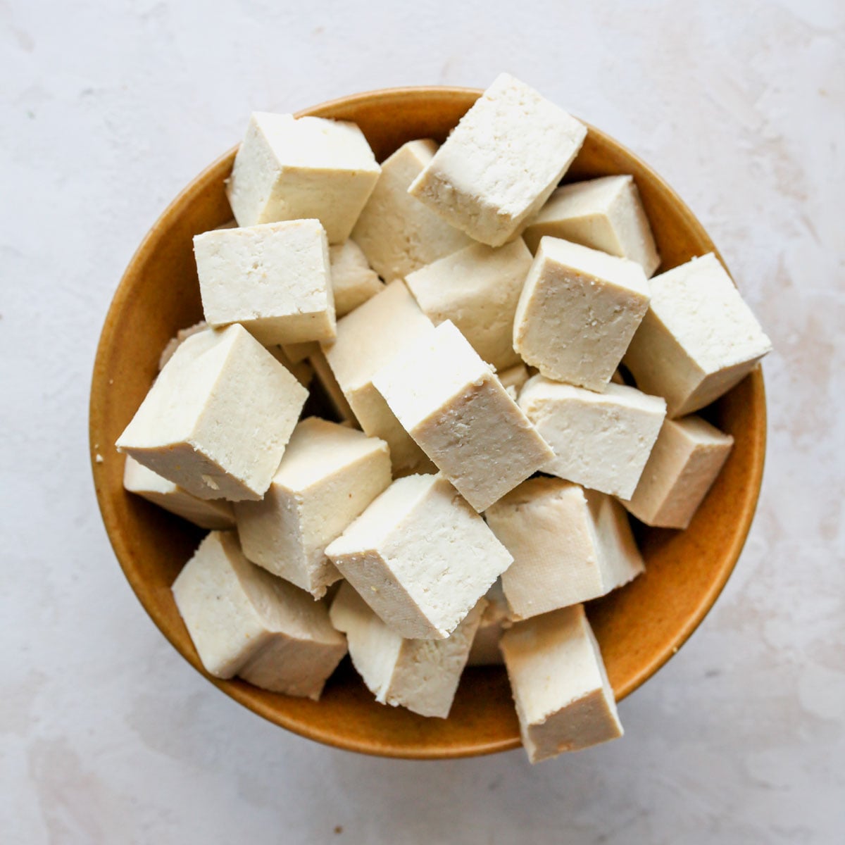 Extra-firm tofu being pressed and cut into cubes