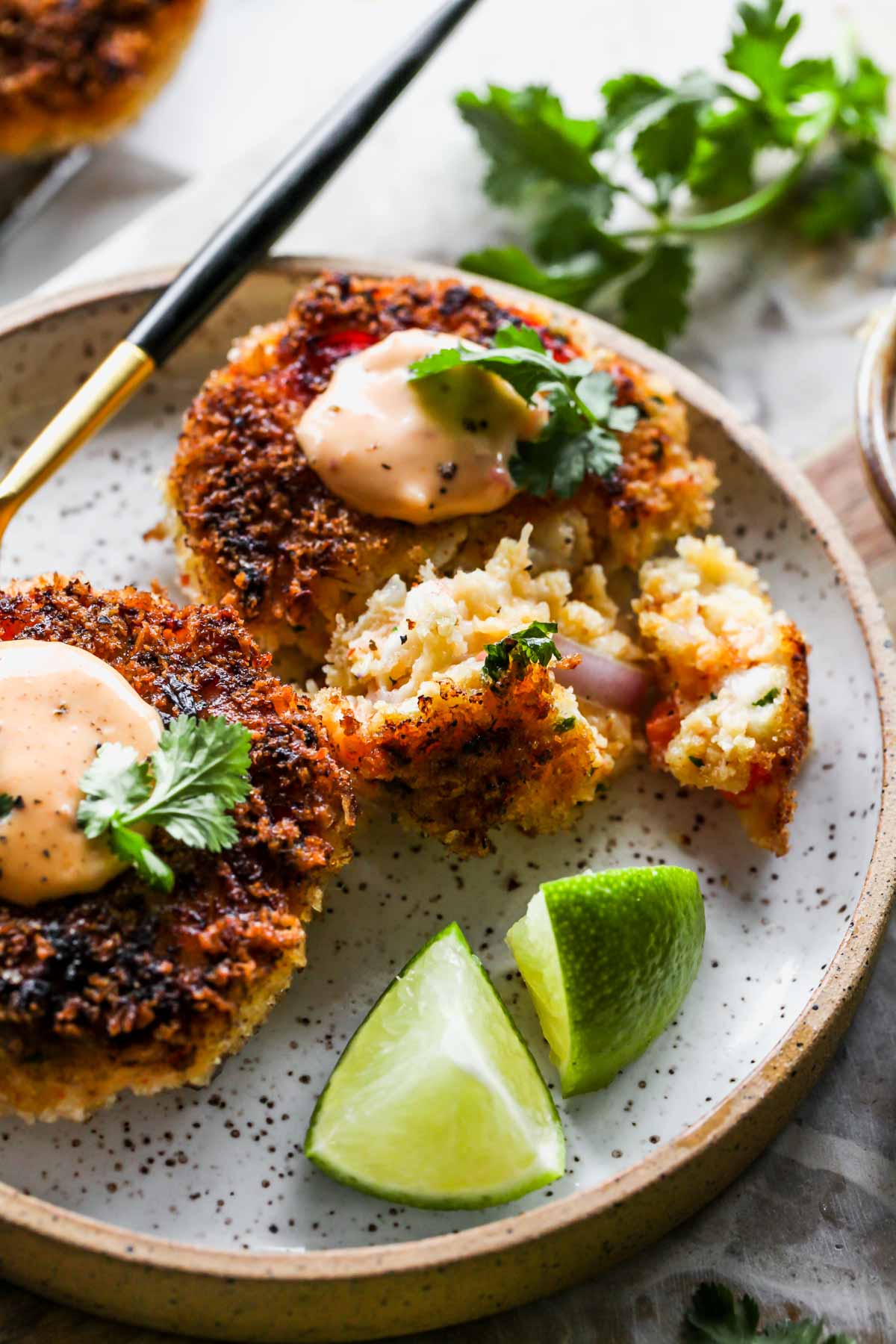 Two shrimp cakes on a plate being cut into with a fork