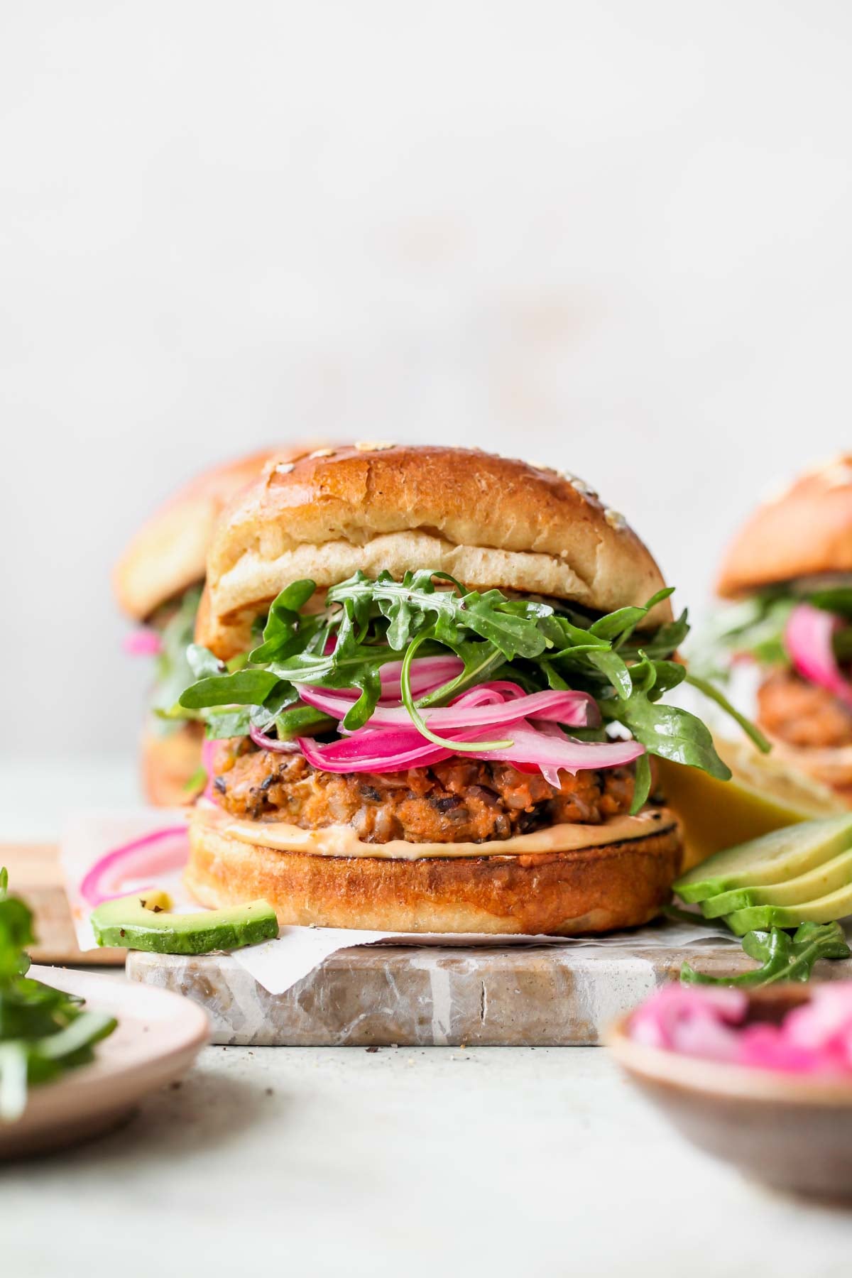 Styled wild rice veggie burger topped with pickled red onion and arugula