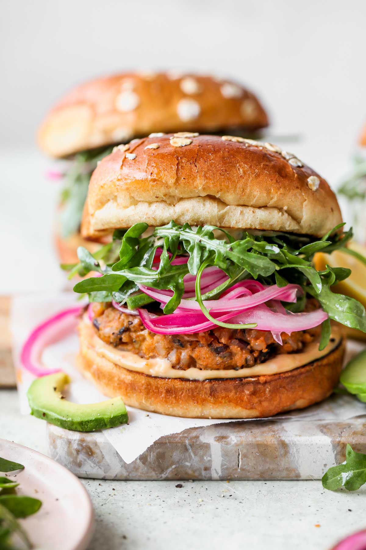 Wild rice patty on a bun topped with tahini sauce, red onion, and arugula