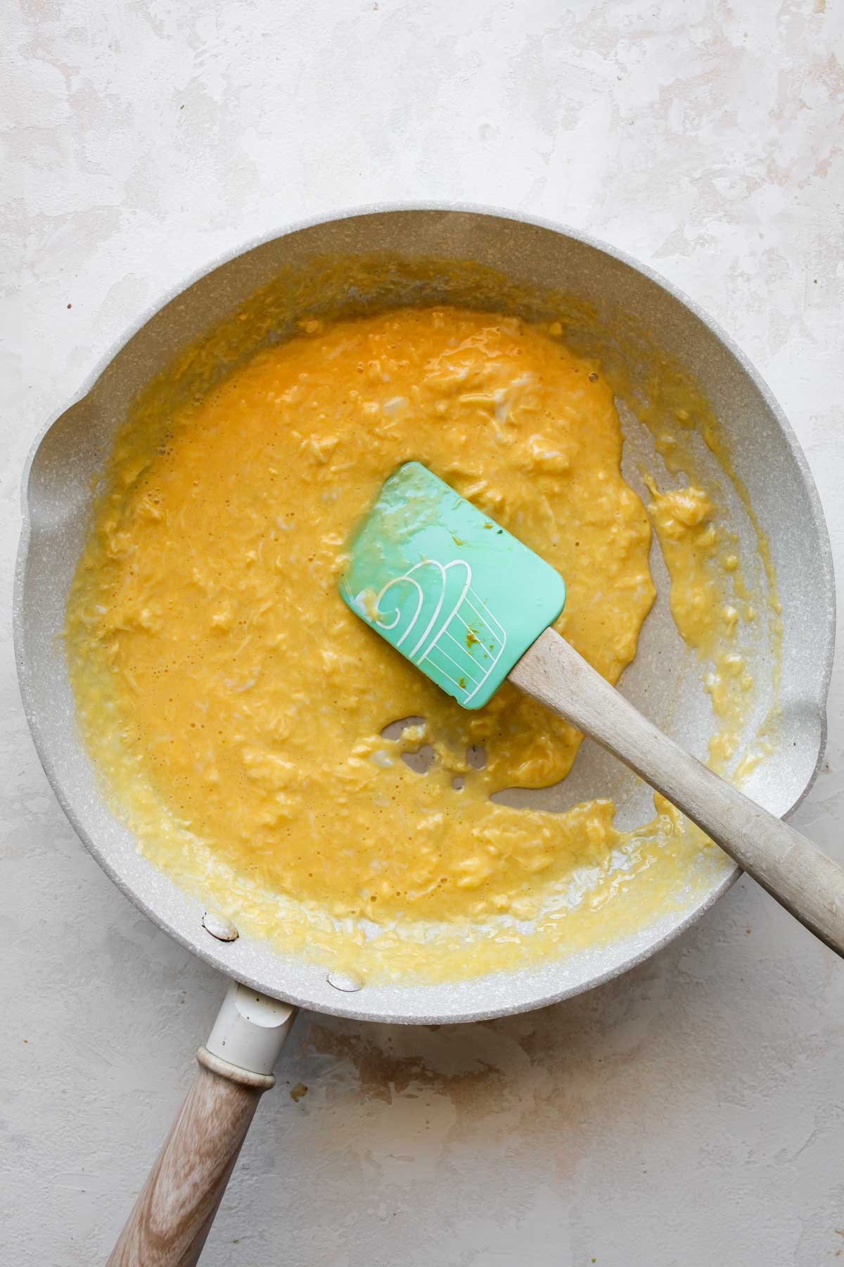 Scrambled eggs being cooked in a white skillet
