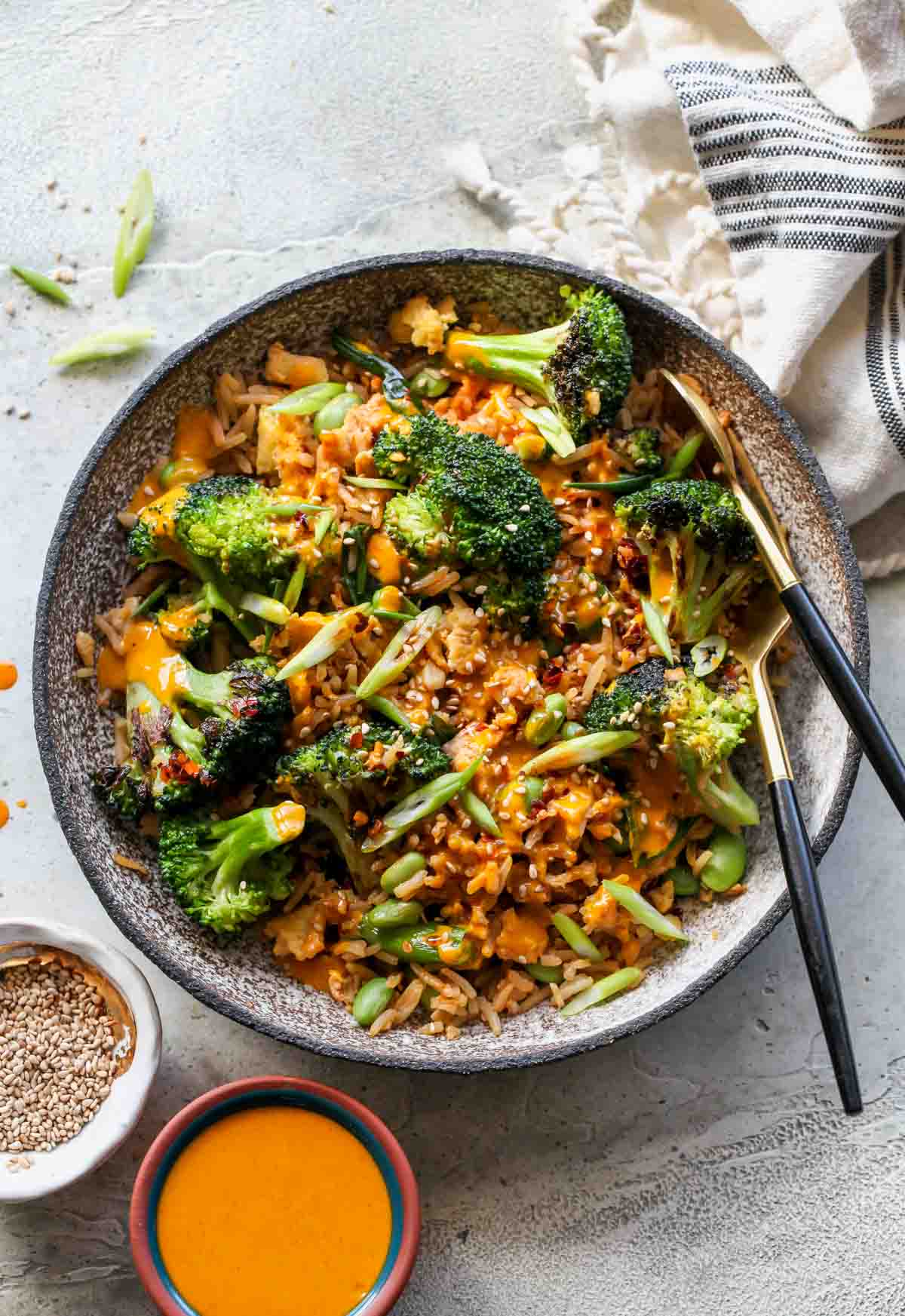 Single serving of broccoli fried rice in a bowl with serving utensils resting on the side