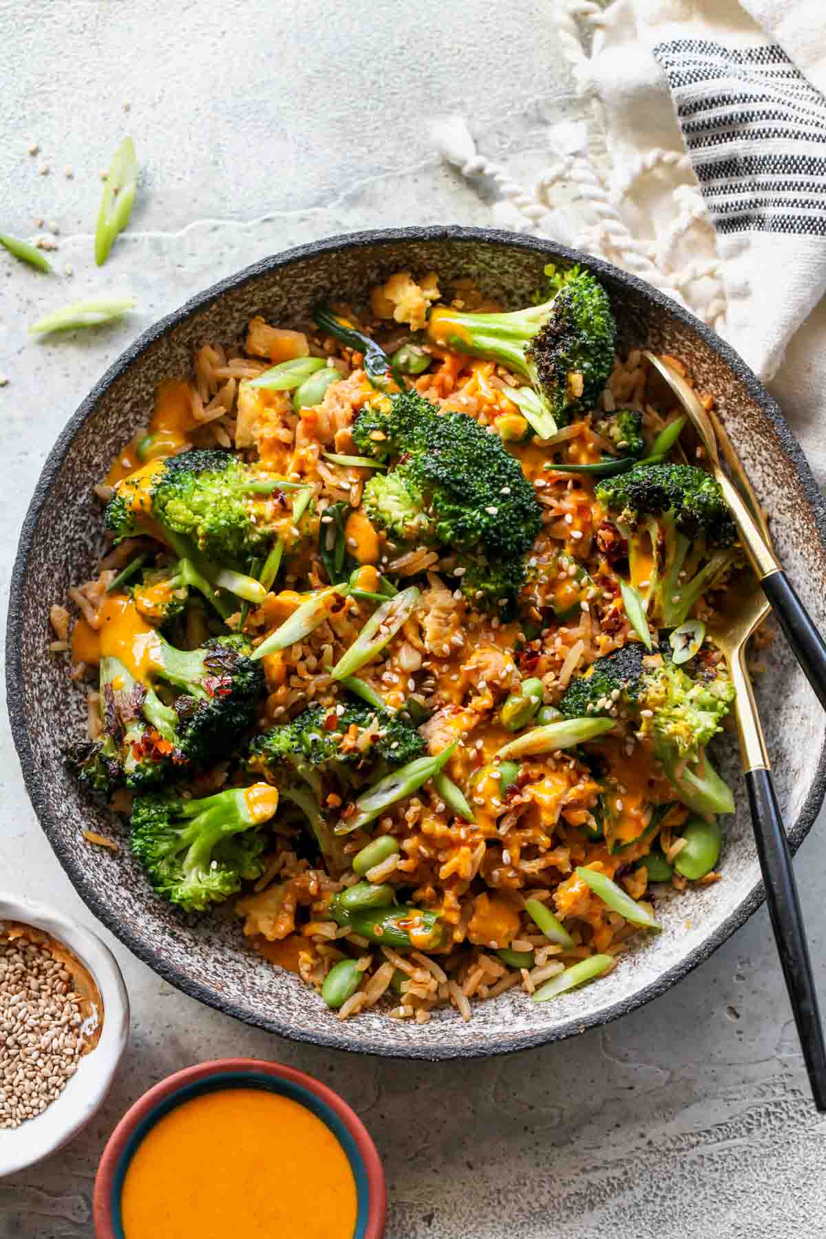 Broccoli fried rice in a grey bowl with sauce drizzled overtop