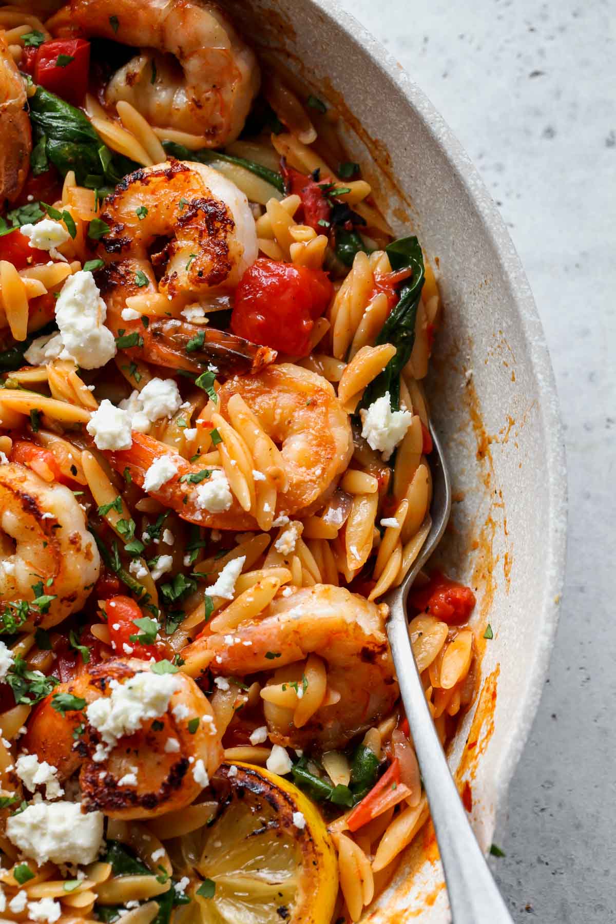 A spoon pulling out a spoonful of harissa shrimp orzo