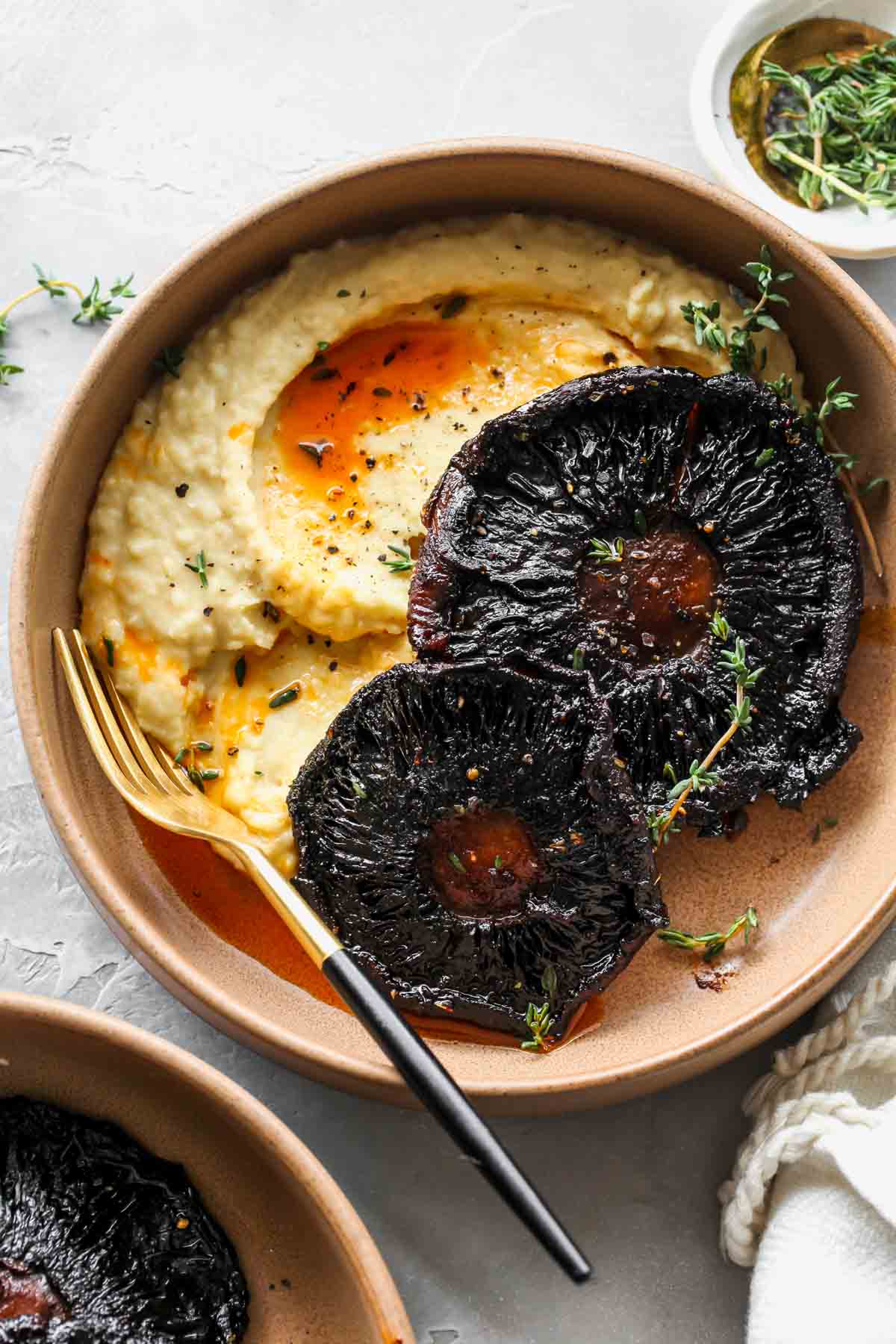 Butter bean mash in a tan bowl topped with two portobello mushrooms
